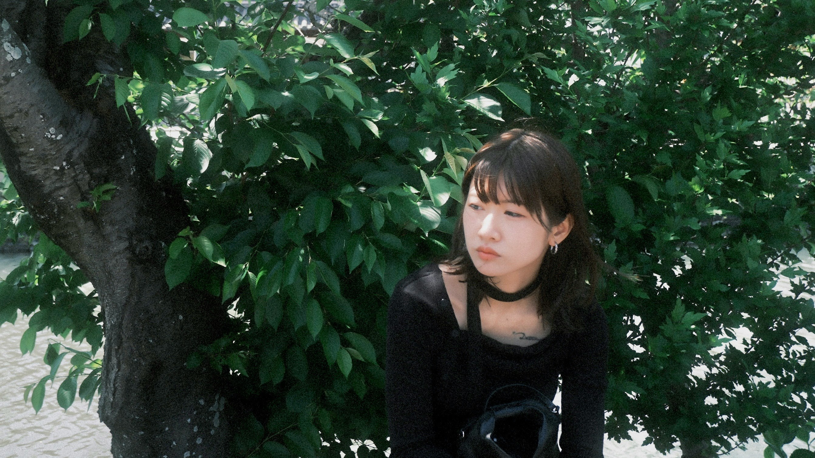 木陰の葉の前で佇む女性