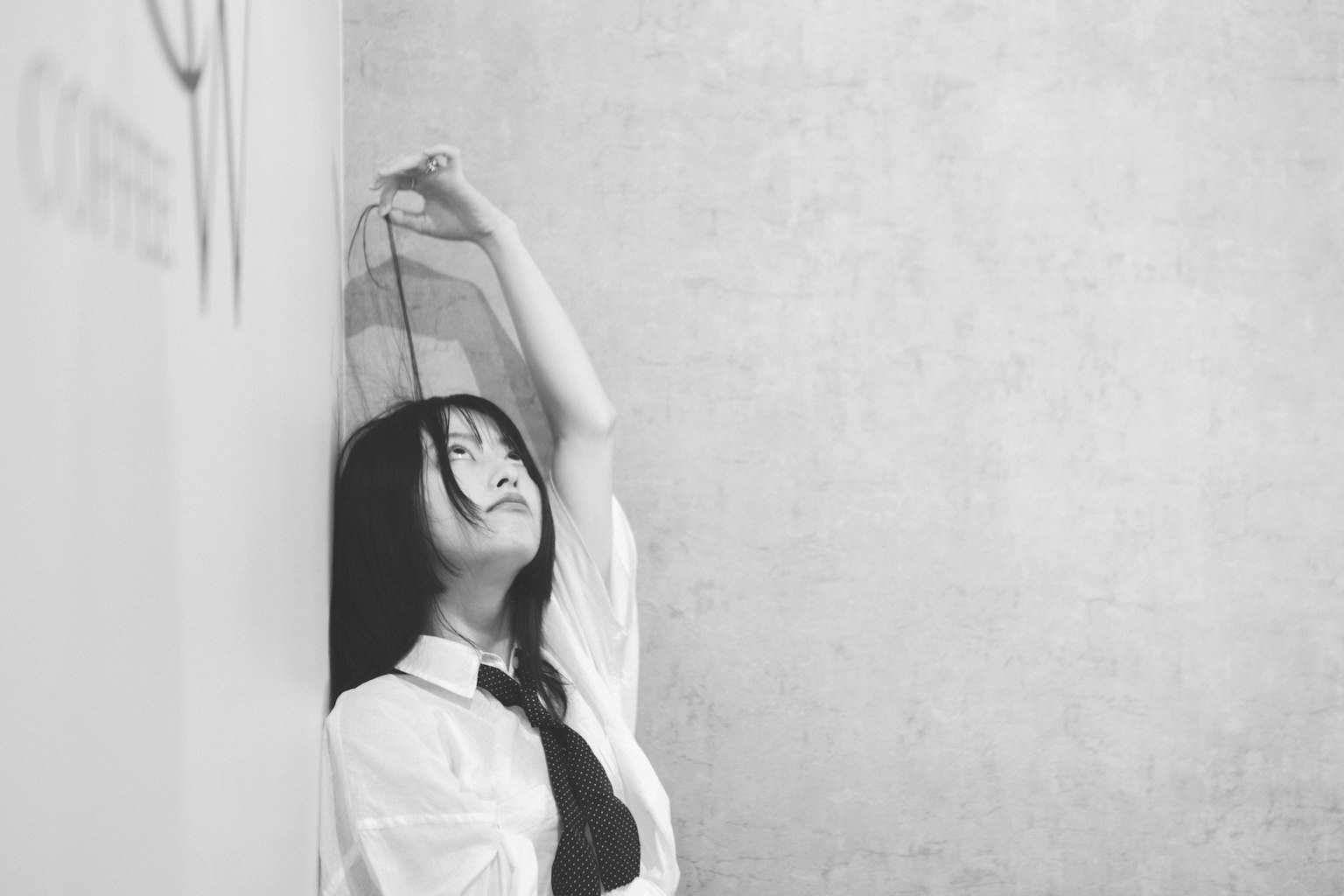 벽에 기대고 머리를 뒤로 젖힌 소녀의 흑백 사진