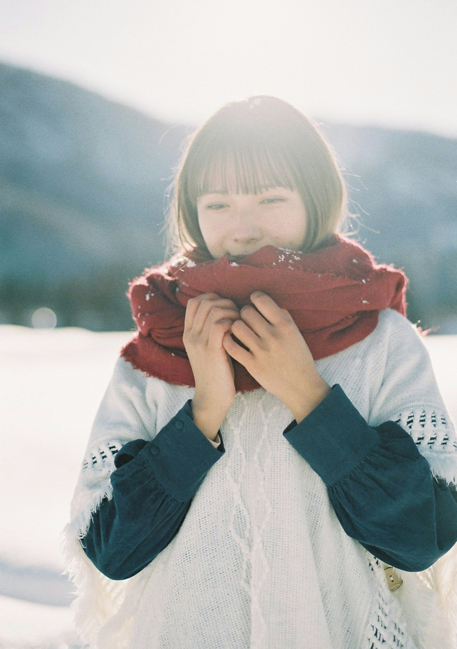 Mujer sonriente sosteniendo una bufanda roja en la nieve