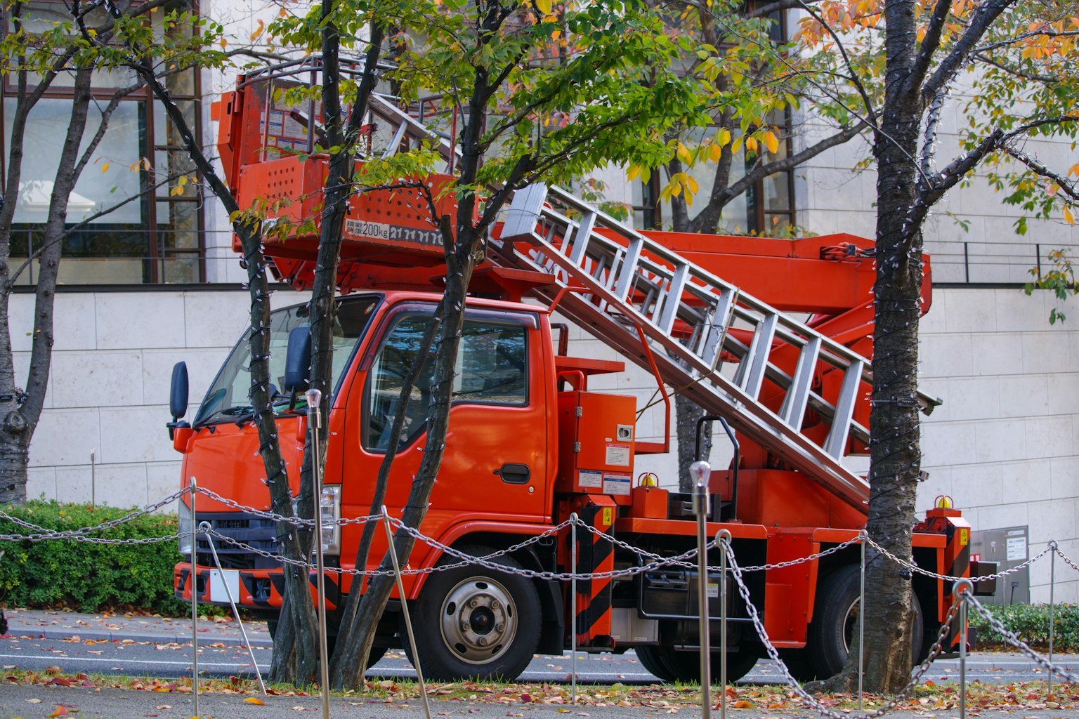 Camion élévateur rouge garé près des arbres de rue