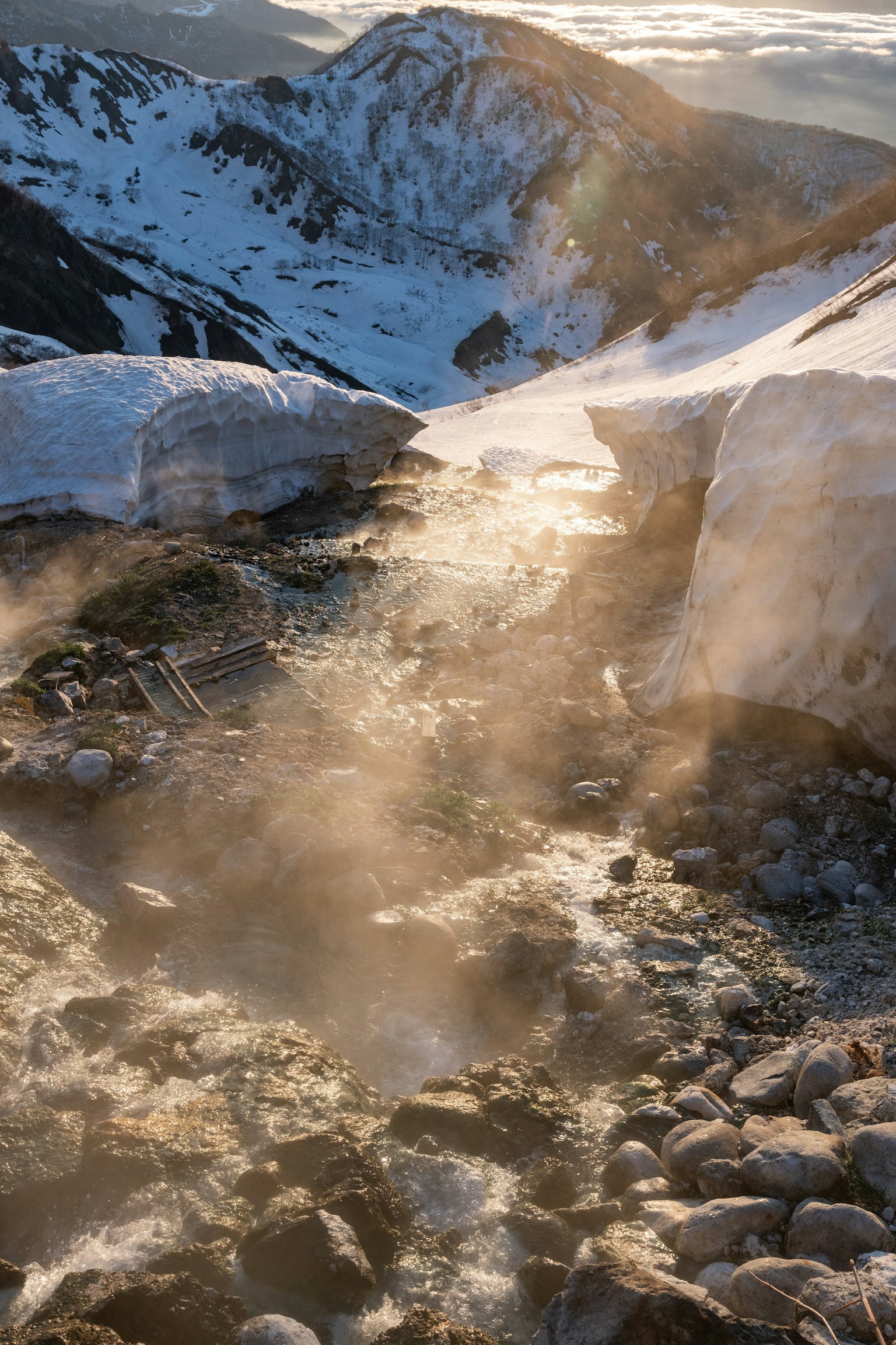 被雪覆盖的山脉与冒蒸汽的河流景观