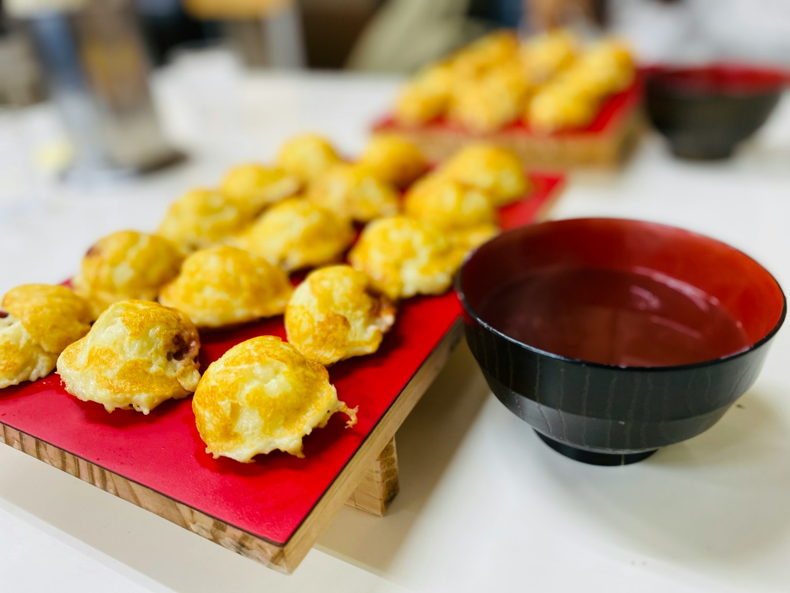 新鲜出炉的小面包放在红色盘子上，旁边有一个黑色碗