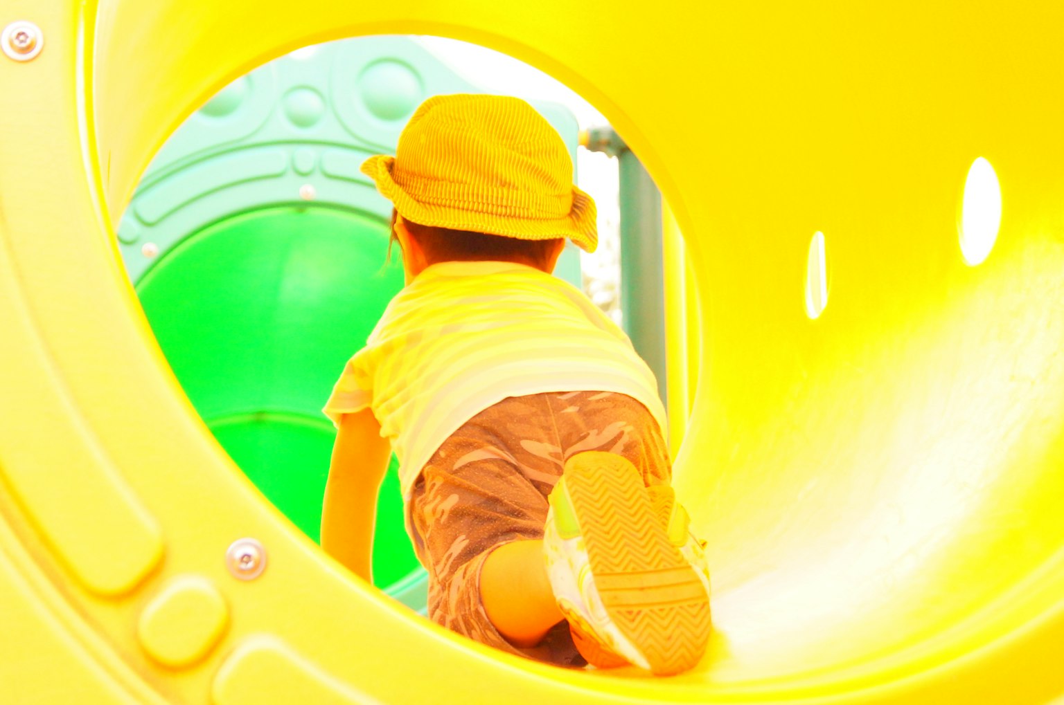 Anak merayap melalui terowongan taman bermain kuning