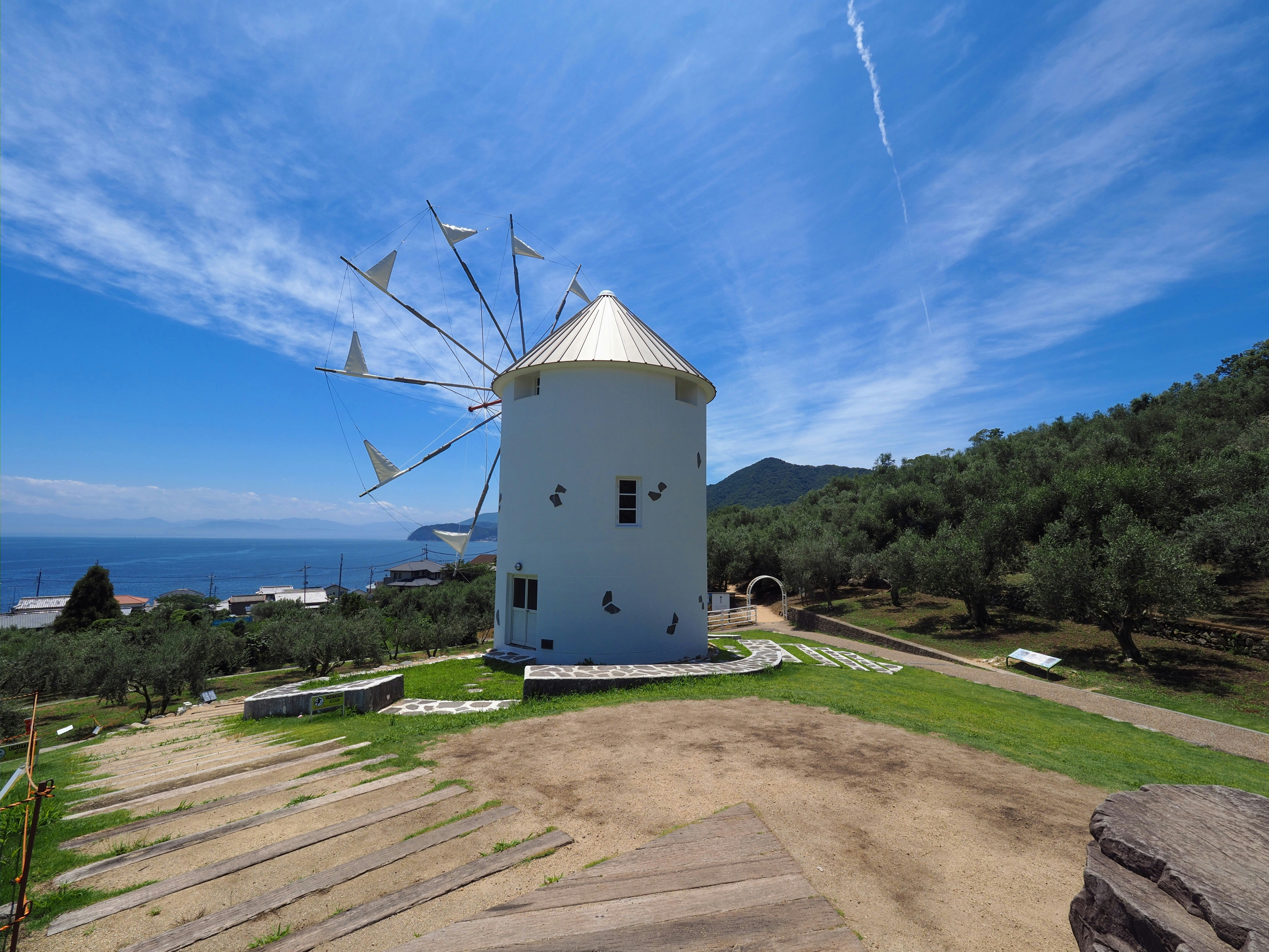 weiße Windmühle auf einem Hügel unter blauem Himmel