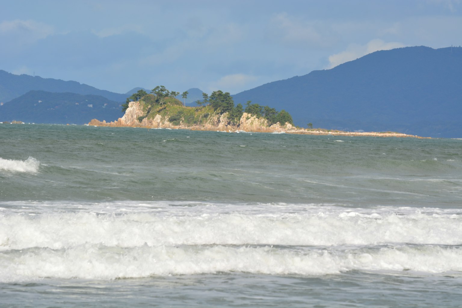 Kleine Insel umgeben von blauem Meer und Wellen