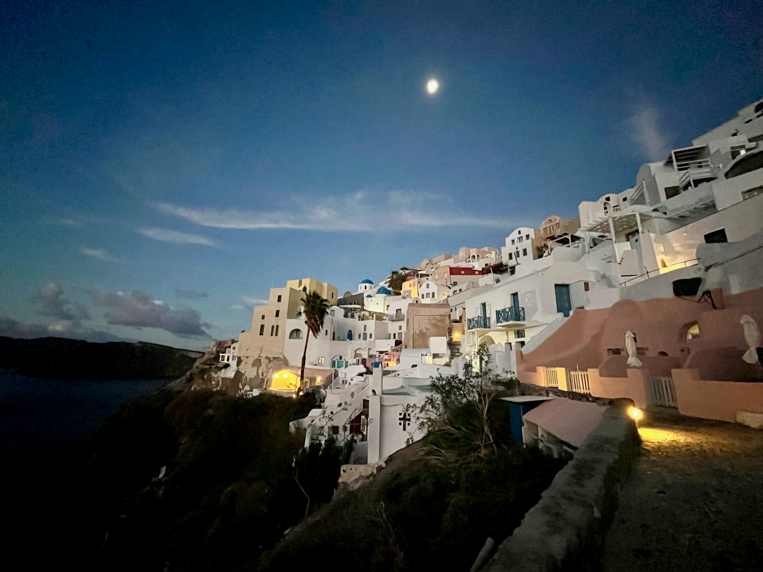 Vista notturna di Santorini con edifici bianchi e luna
