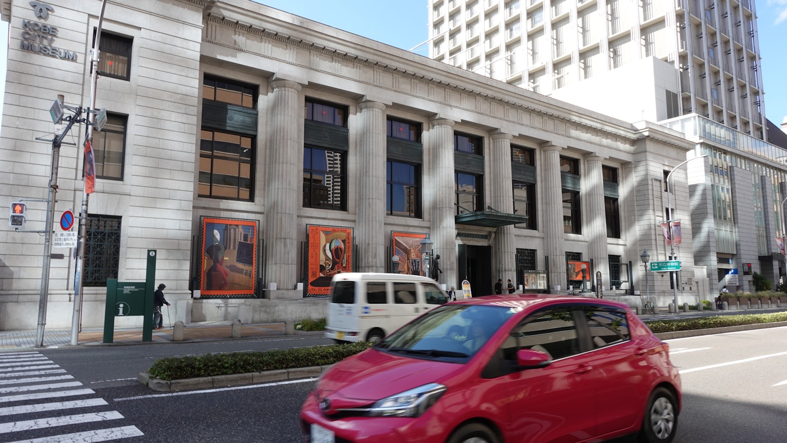 街道景观，展示一辆红色汽车和一座历史建筑的外观