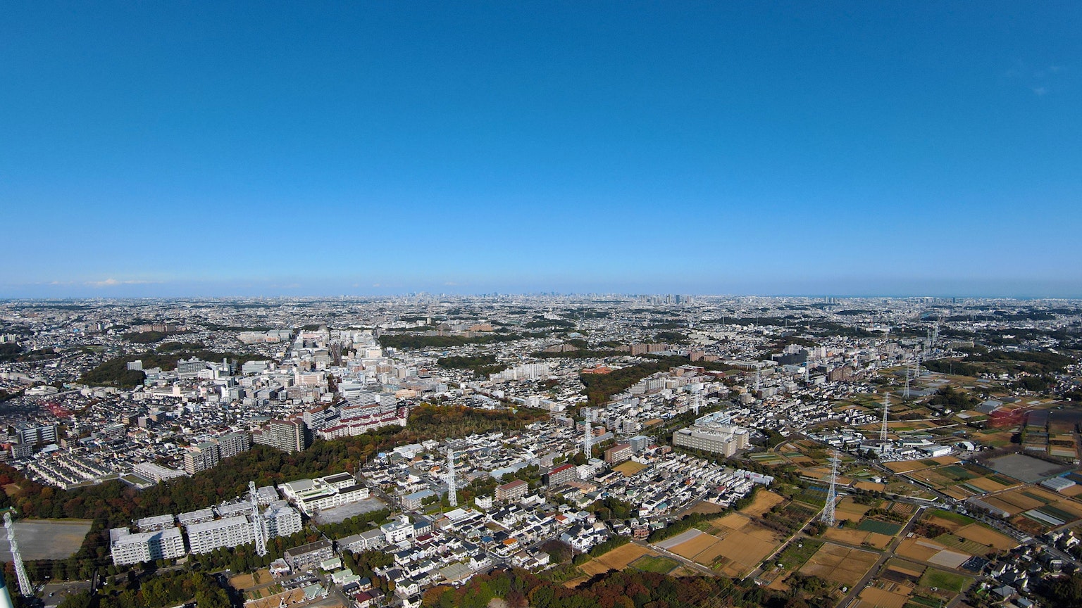 Vista panoramica di una città che si estende sotto un cielo blu con edifici e aree verdi