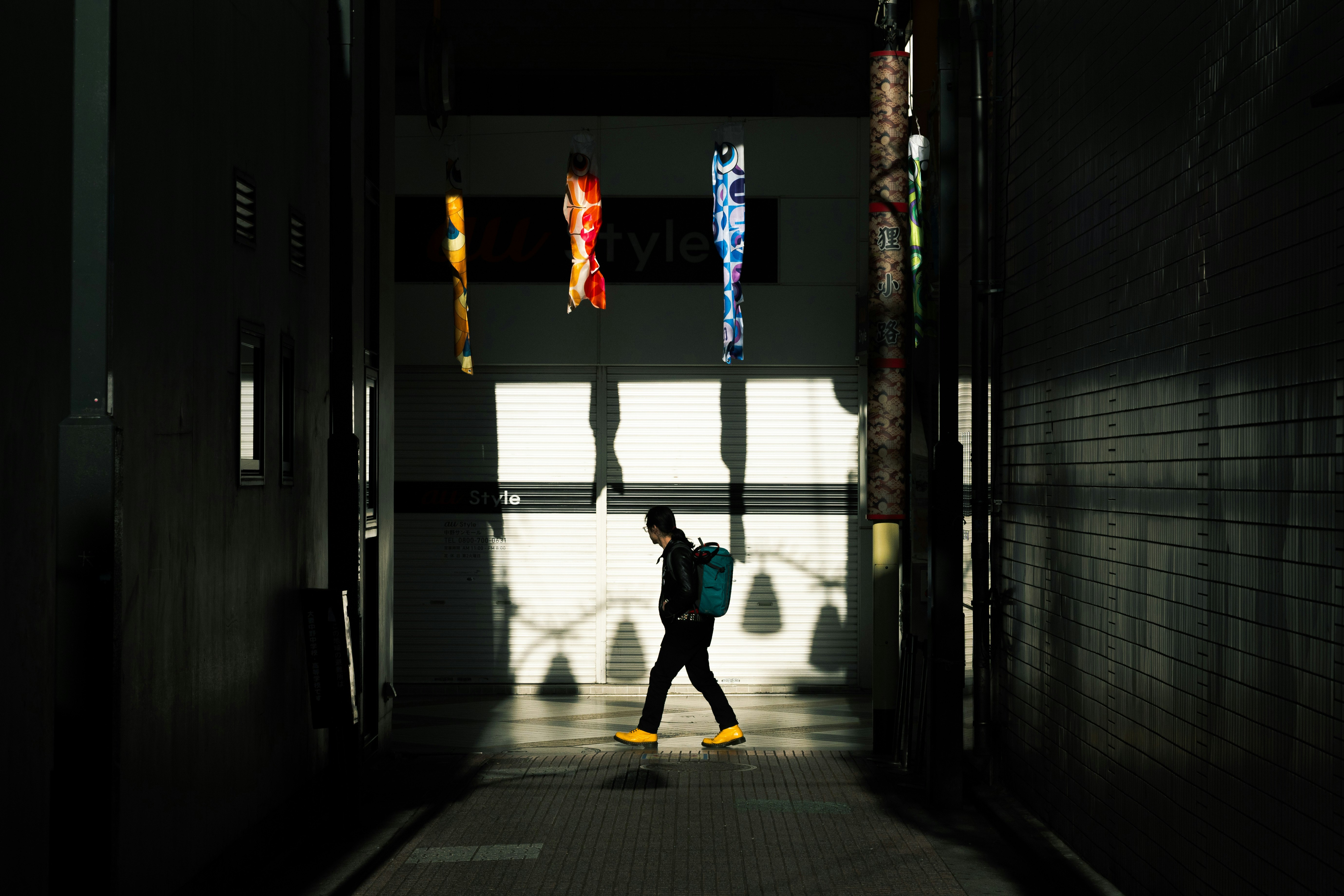 silhouette of a person walking down a narrow alley
