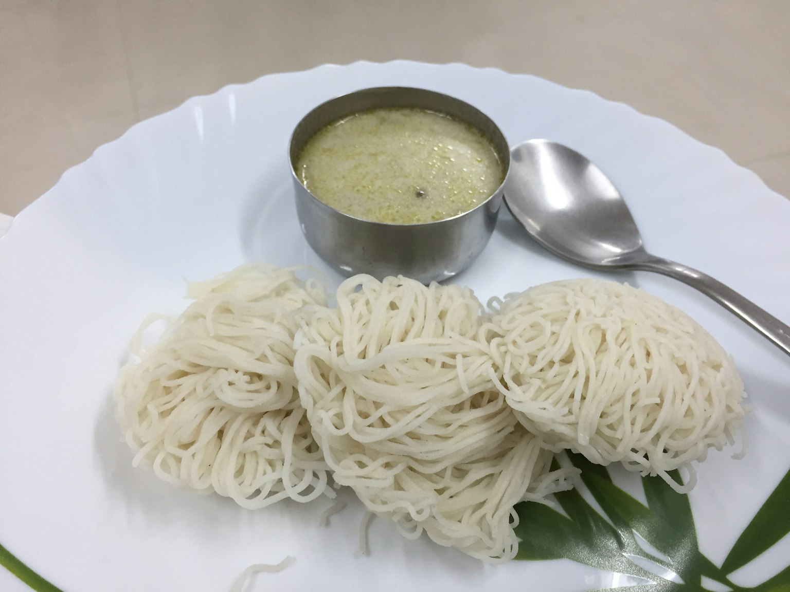 Fideos blancos finos servidos con una pequeña taza de salsa