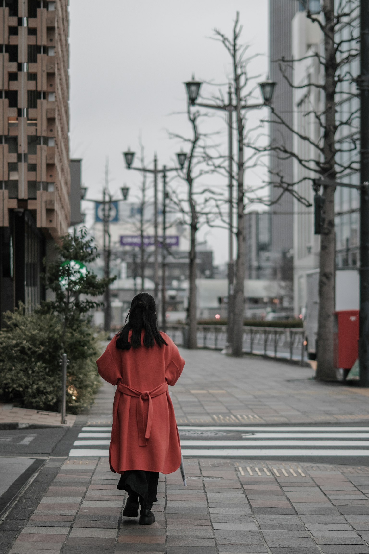 Una donna in un cappotto rosso che cammina in una strada urbana