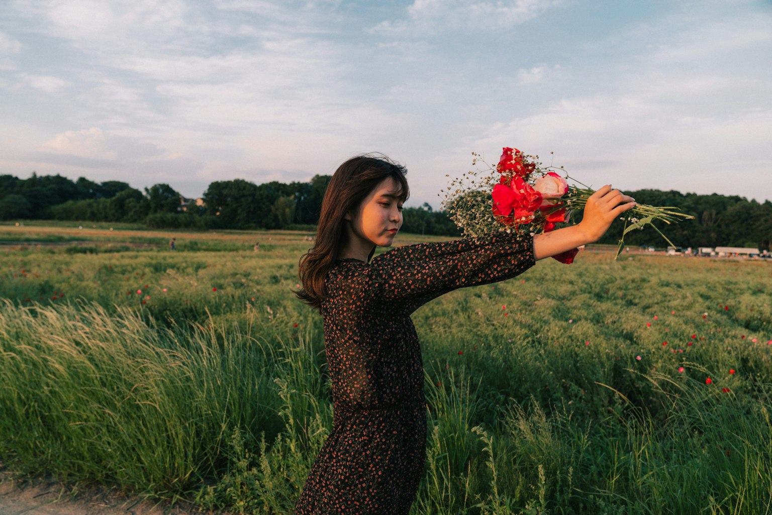 Donna che tiene un bouquet in un campo verde