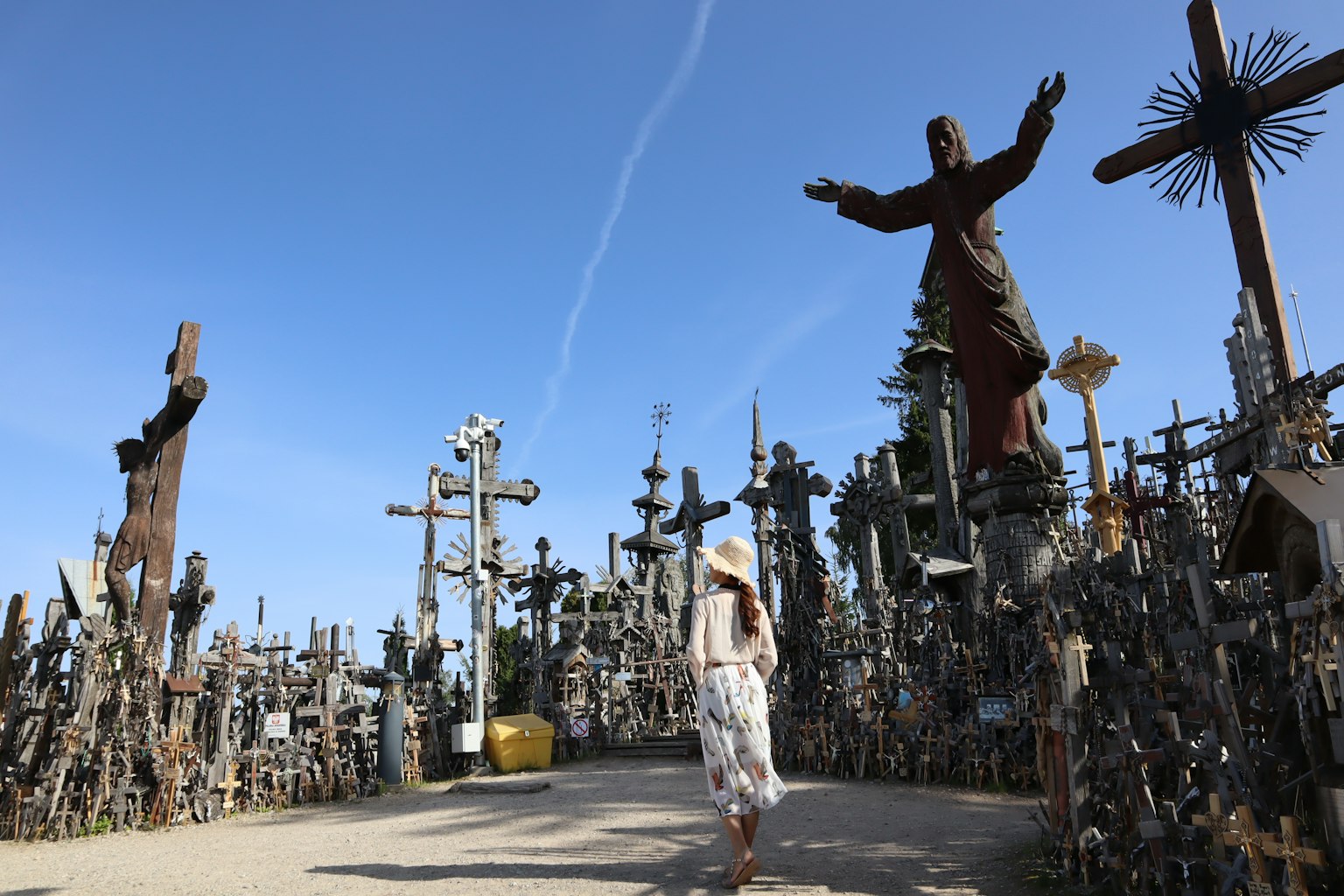 Una mujer caminando a través de un paisaje lleno de cruces y estatuas