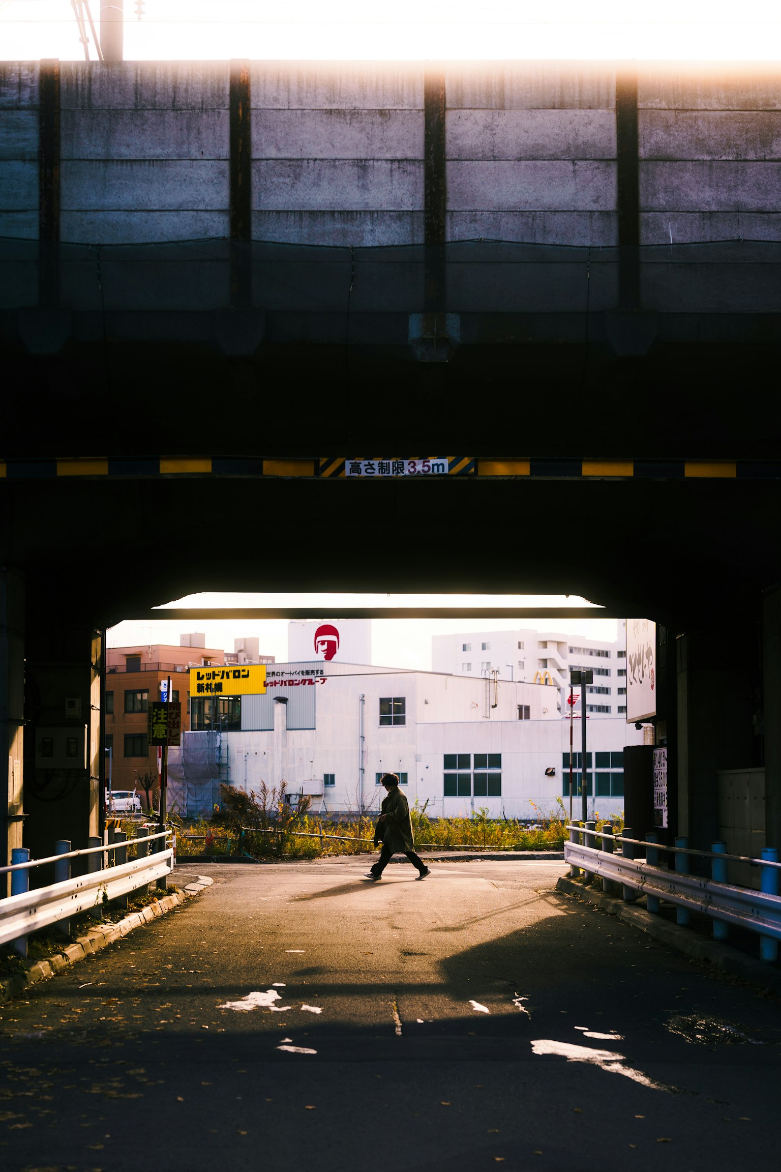 Silhouette d'une personne marchant sous un pont avec la lumière du soleil qui filtre