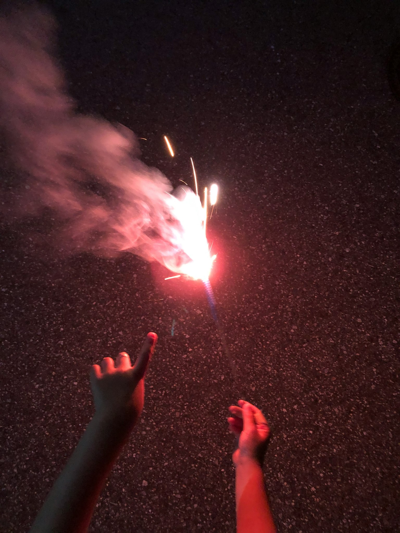 Mani che tengono un fuoco d'artificio con fumo in un ambiente scuro