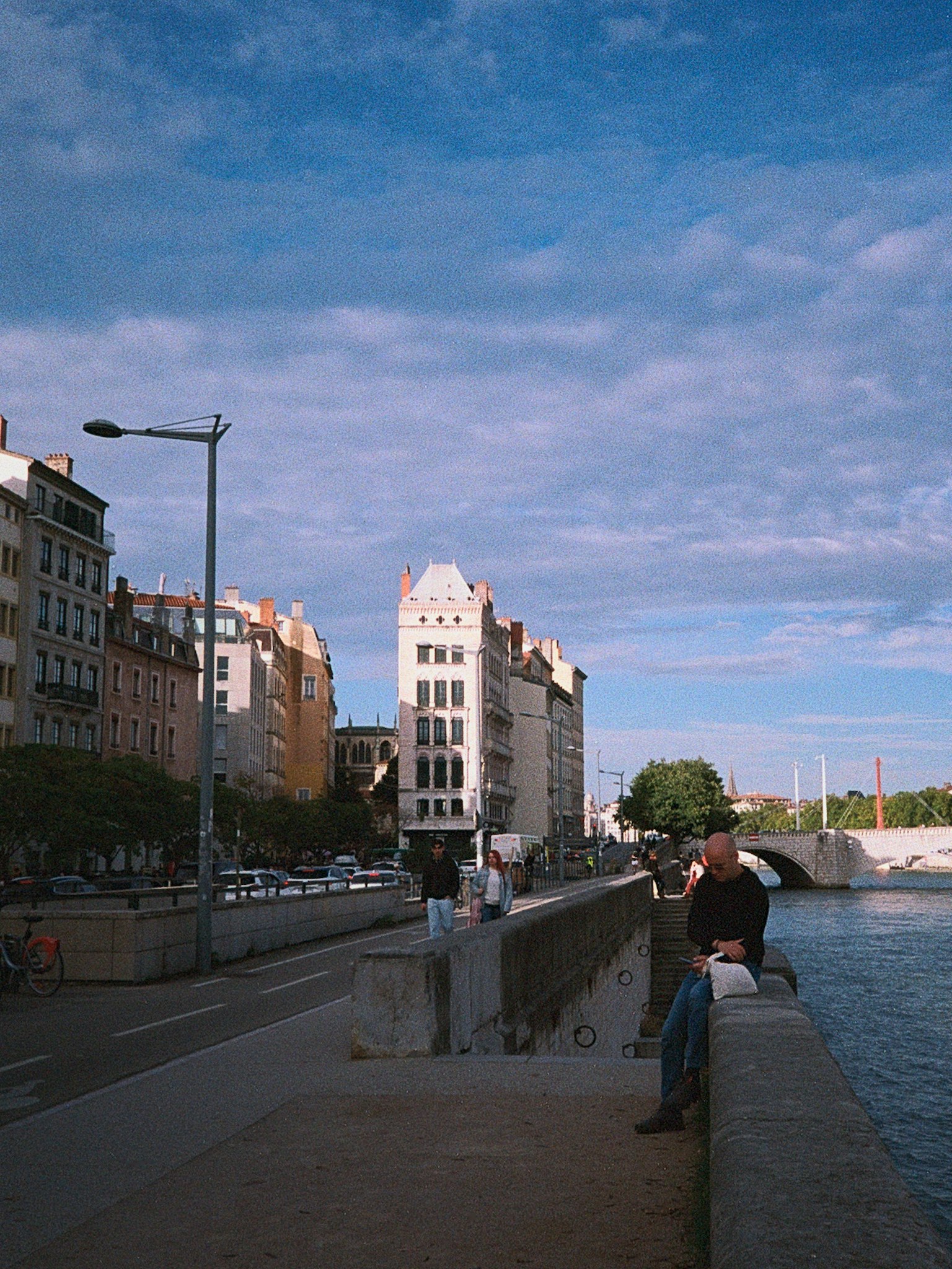 Menschen sitzen entlang des Ufers mit Gebäuden und blauem Himmel