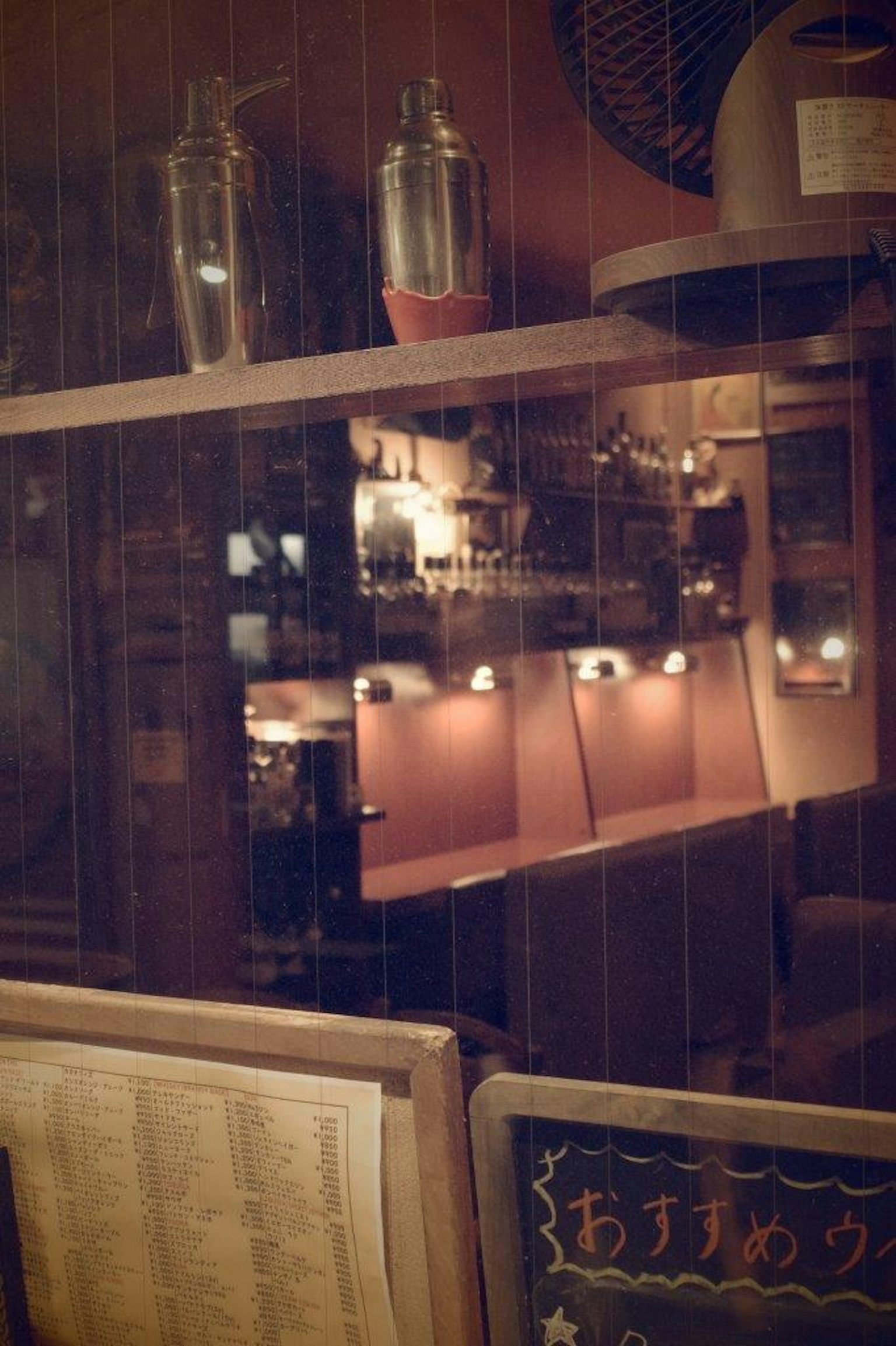 Innenansicht einer schwach beleuchteten Bar mit Regalen und beleuchteten Flaschen