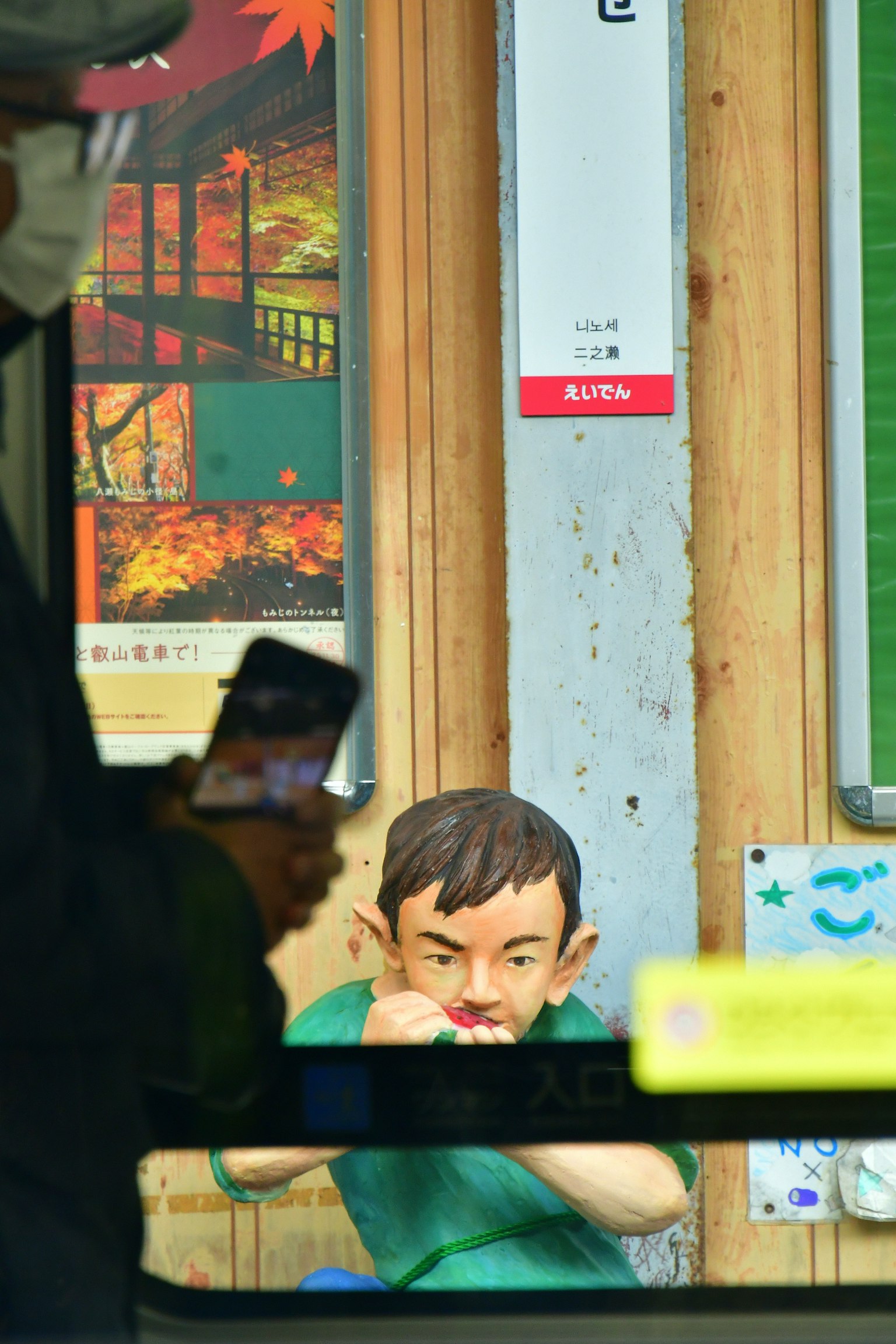 窓の外から見た人形のような少年が歯を磨いている様子と背景のポスター