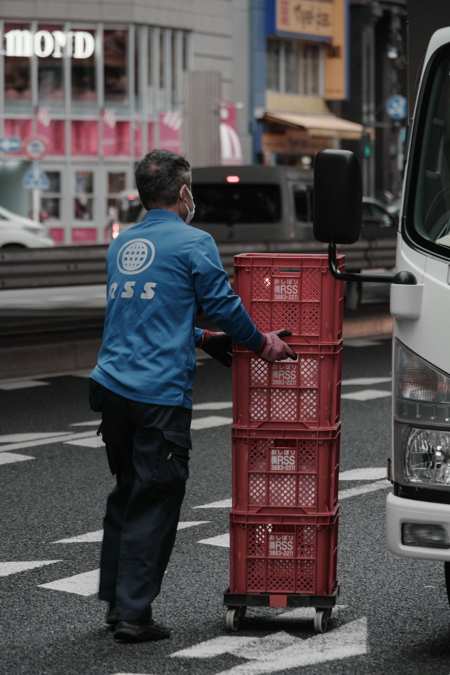 Worker pushing red crates in a city street