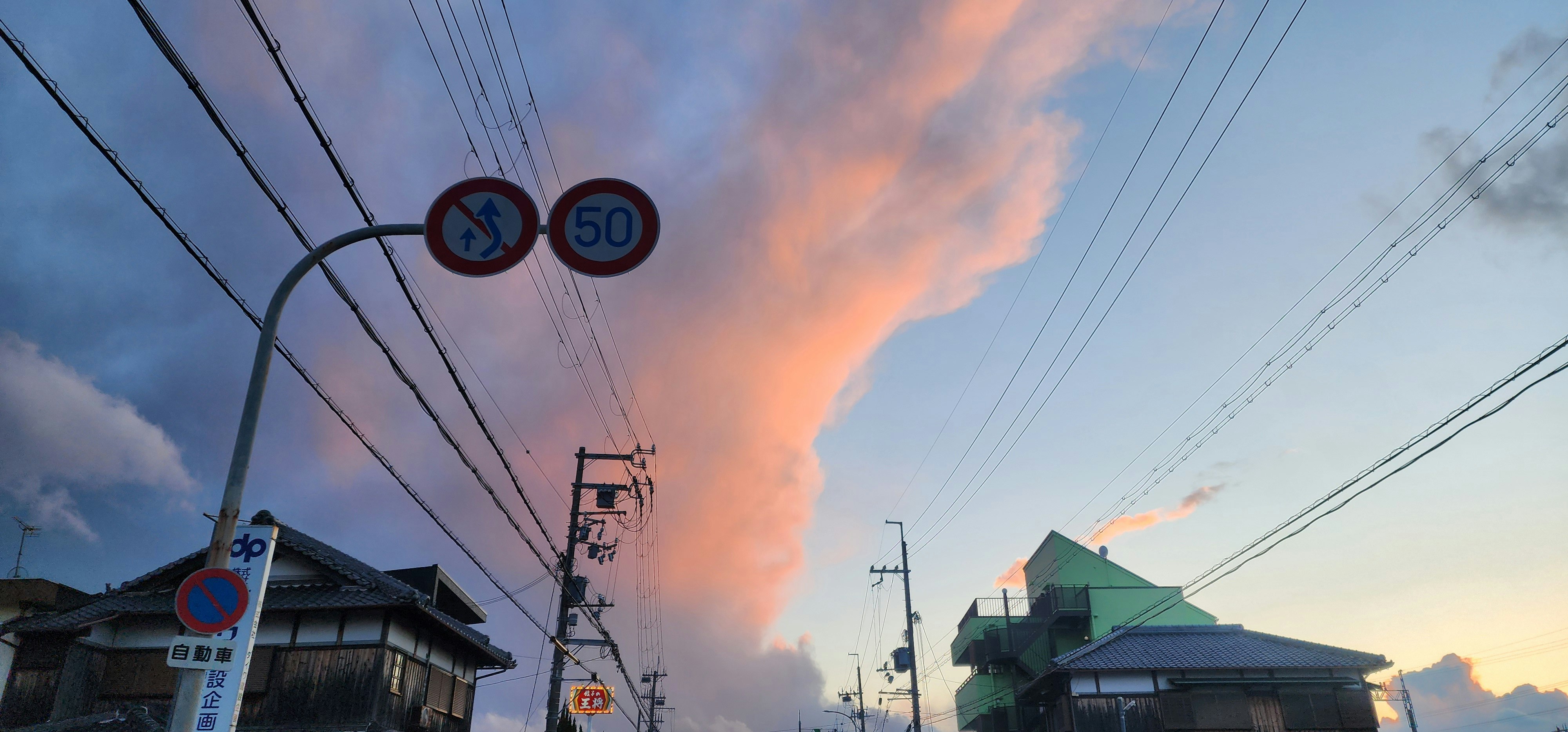 車窓から見える春の嵐の空と電線のある街並み