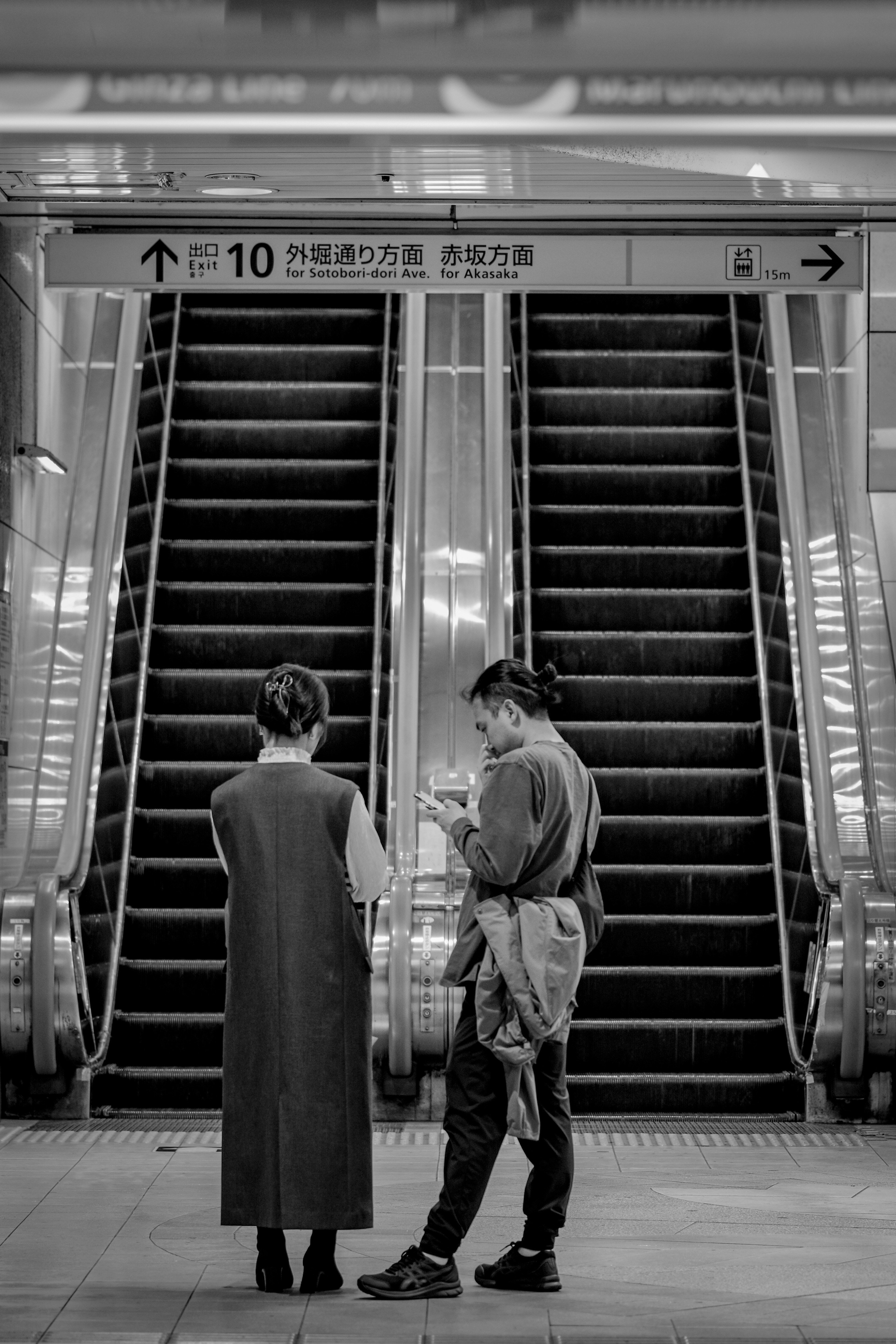 メトロの駅構内でエスカレーター前に立つ人々