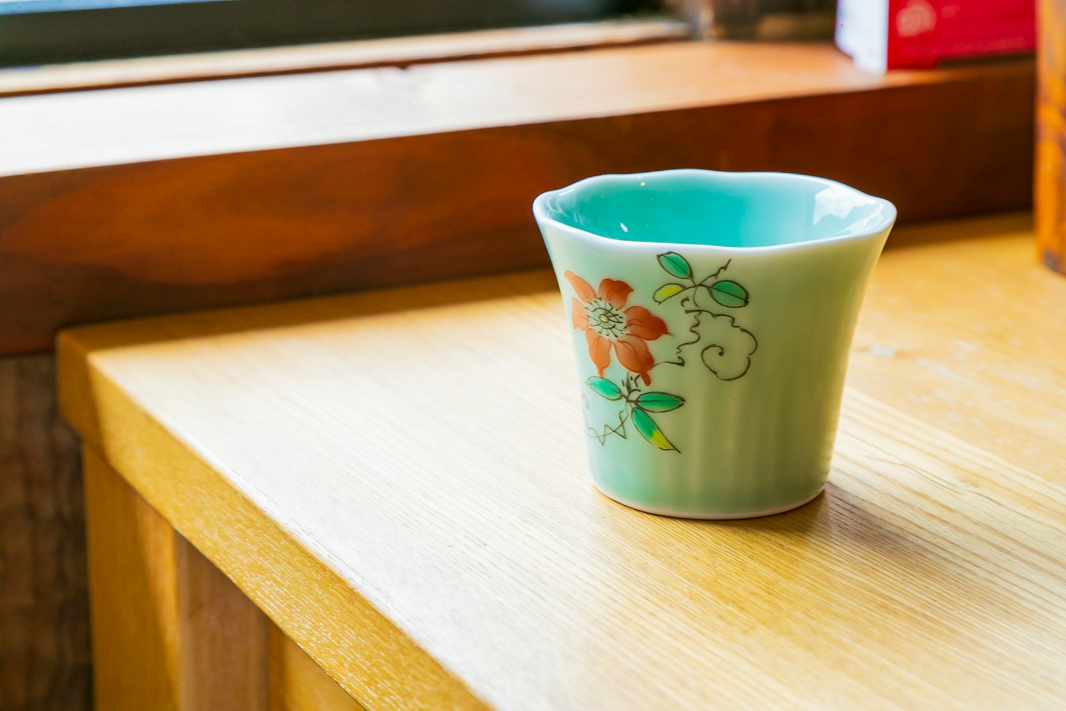 青い花模様の陶器のカップが木のテーブルの上に置かれている