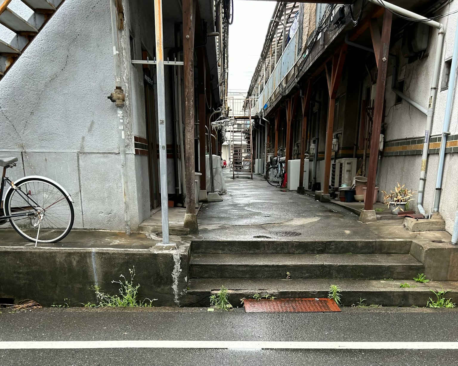 Narrow alley with wet stone pavement and old buildings lined up bicycle on the left side