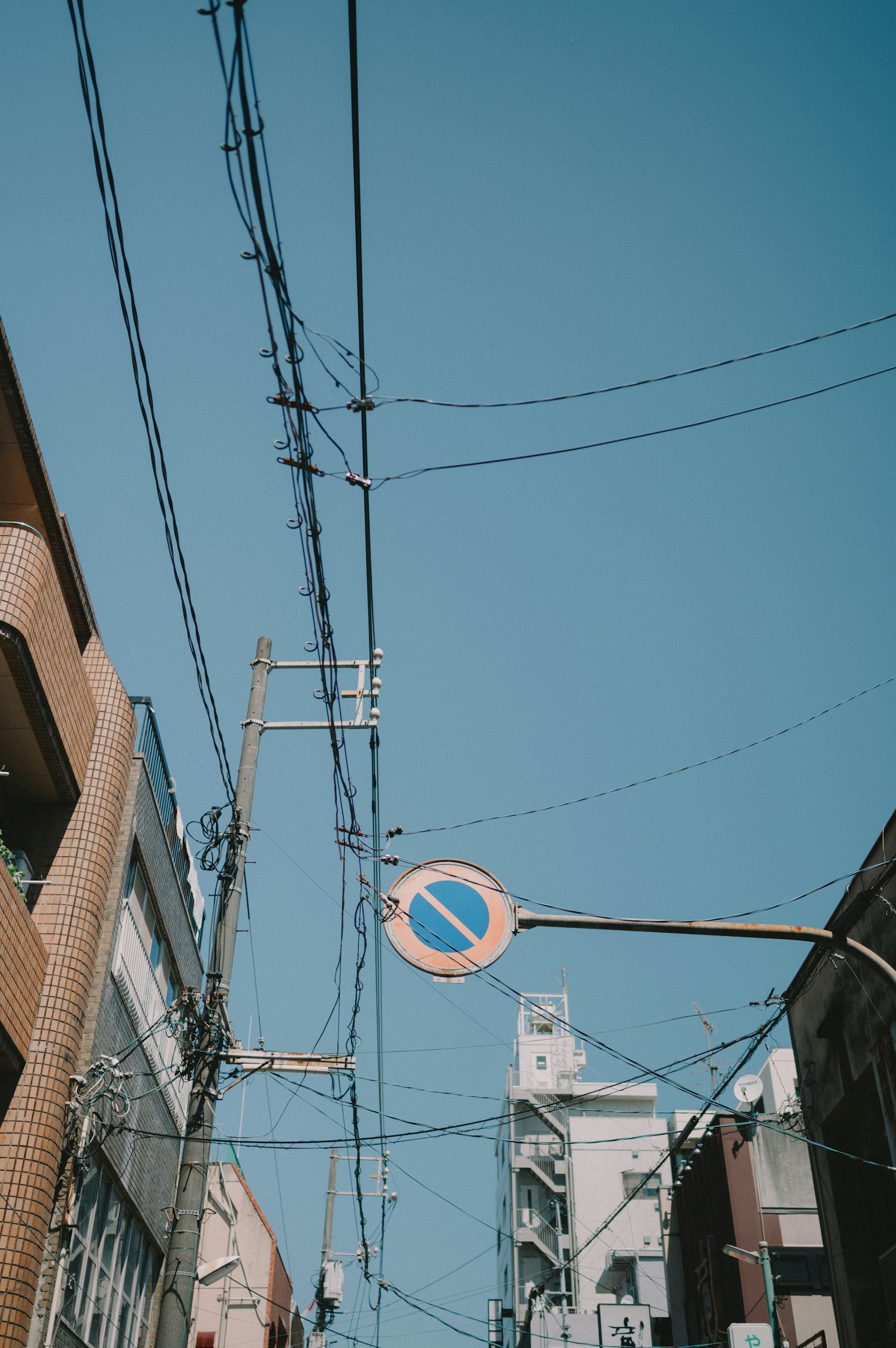 Power lines and a no entry sign under a blue sky
