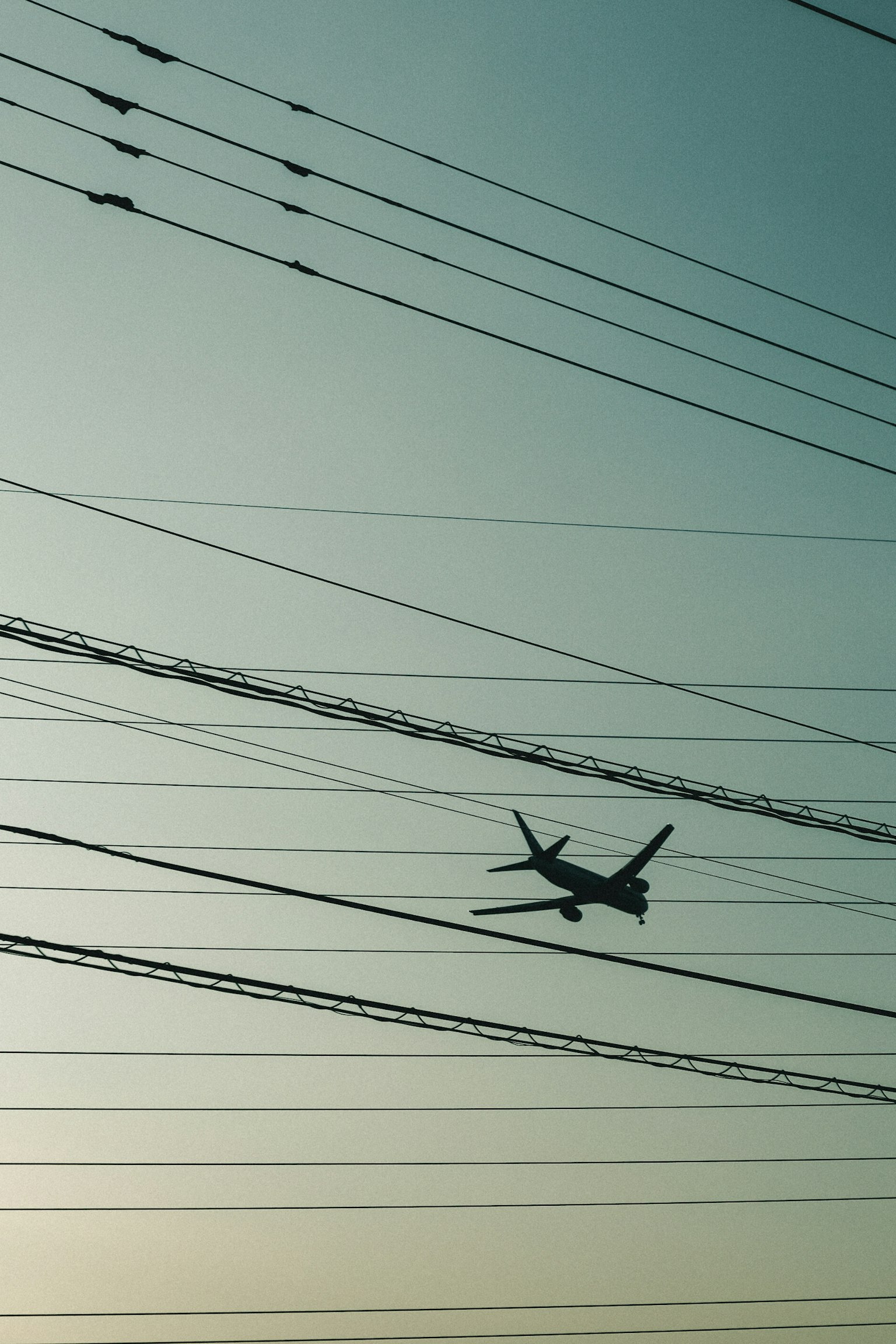 Silhouette eines Flugzeugs, das zwischen Stromleitungen fliegt