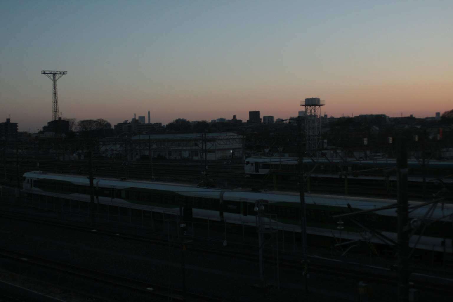 Urban landscape featuring a railway station and buildings at dusk