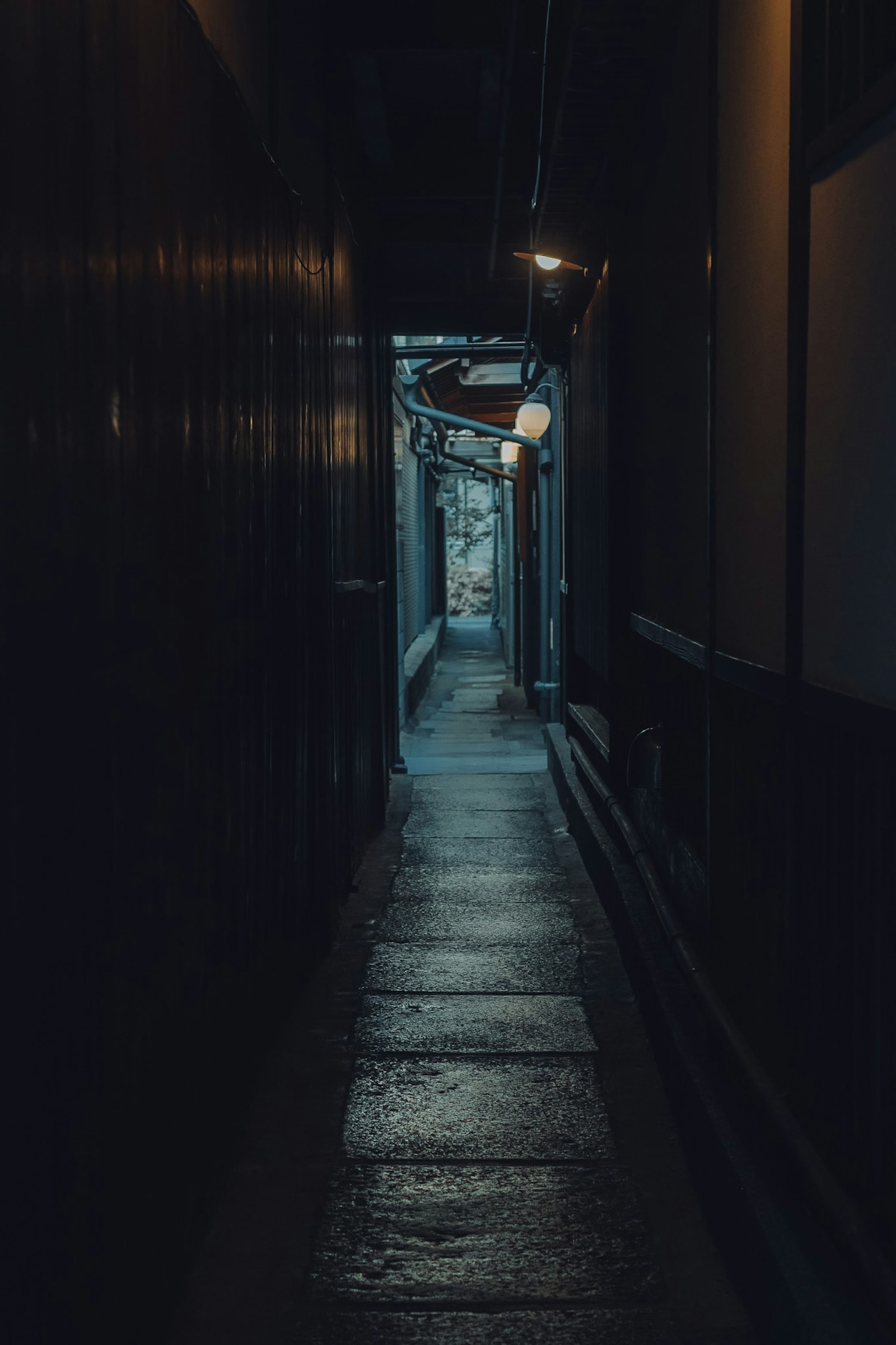 Un callejón estrecho débilmente iluminado con luces en la pared que iluminan el camino