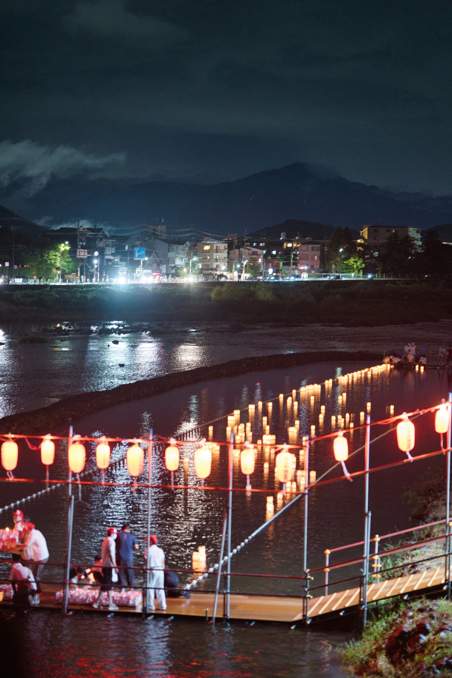 夜晚河面上漂浮的红灯笼和附近的人