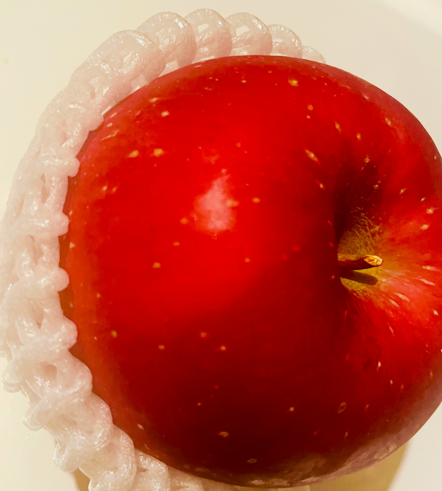 Mela rossa circondata da un imballaggio di plastica bianca