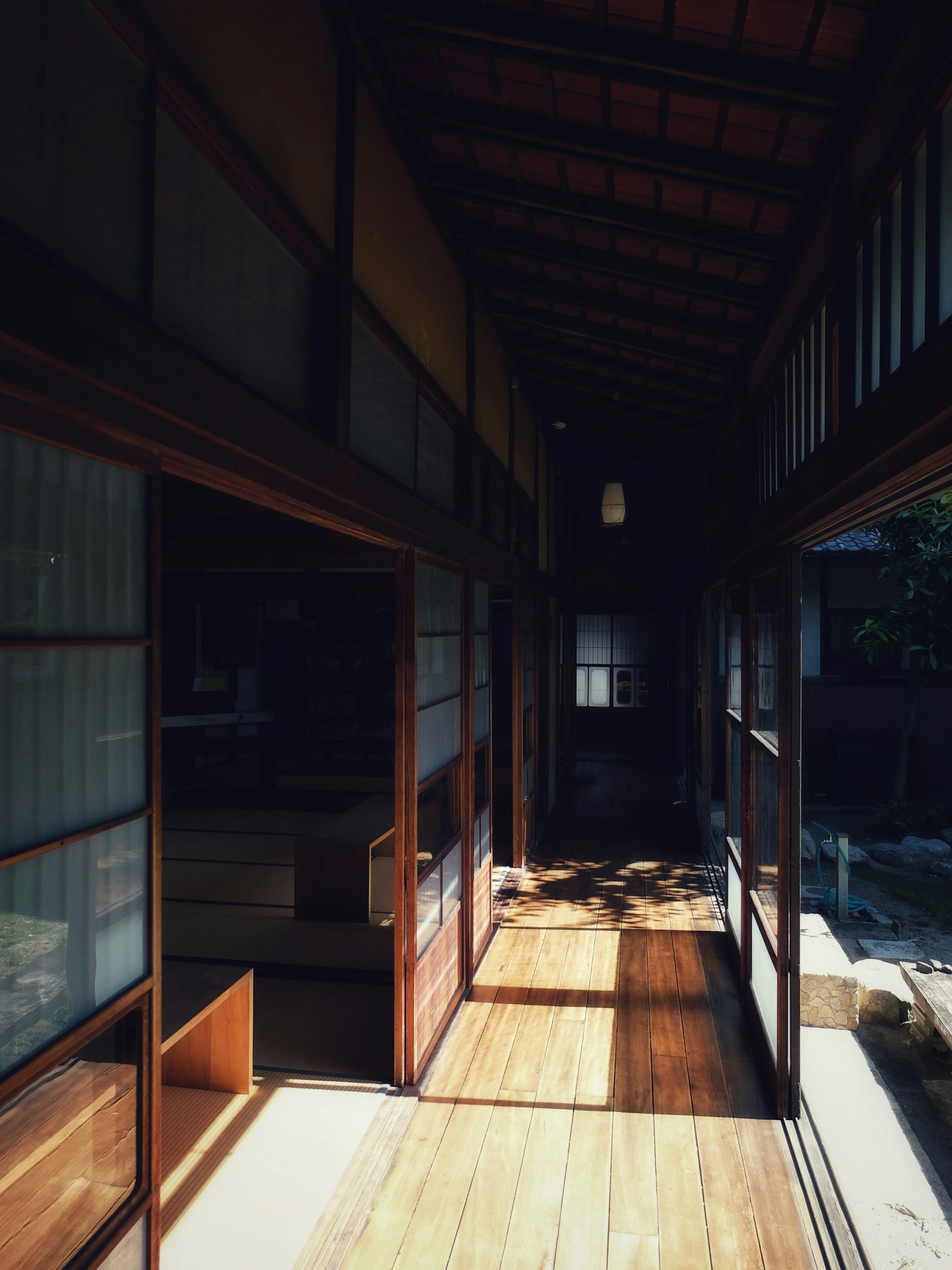 Lorong rumah tradisional Jepang dengan lantai kayu dan dinding kaca