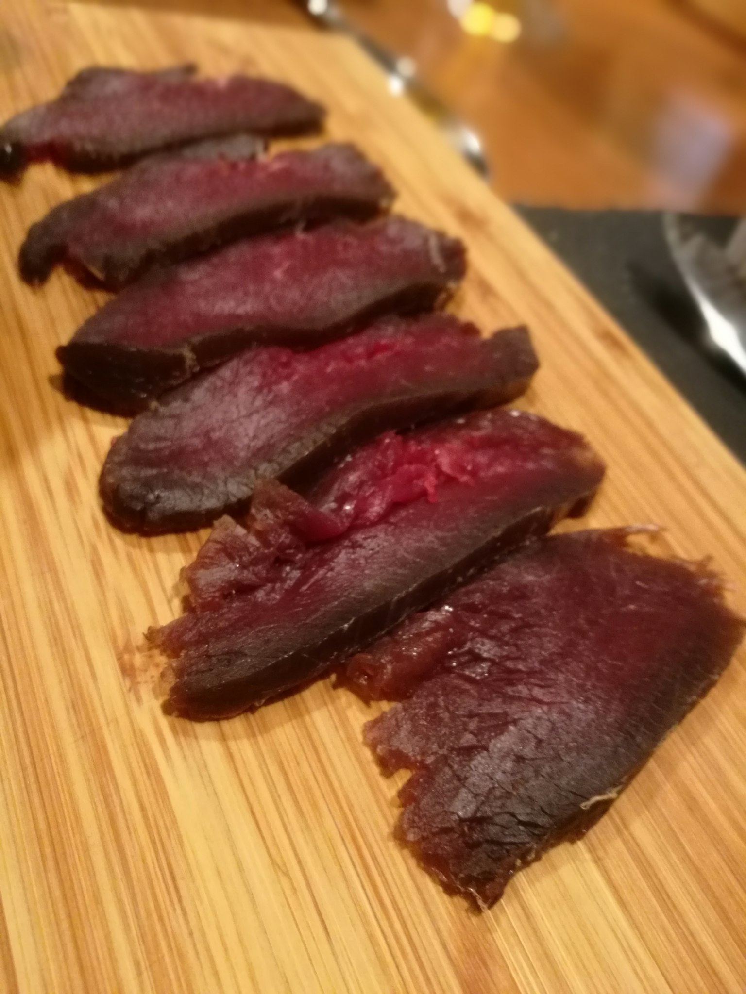 Carne seca en rodajas dispuesta sobre una tabla de madera