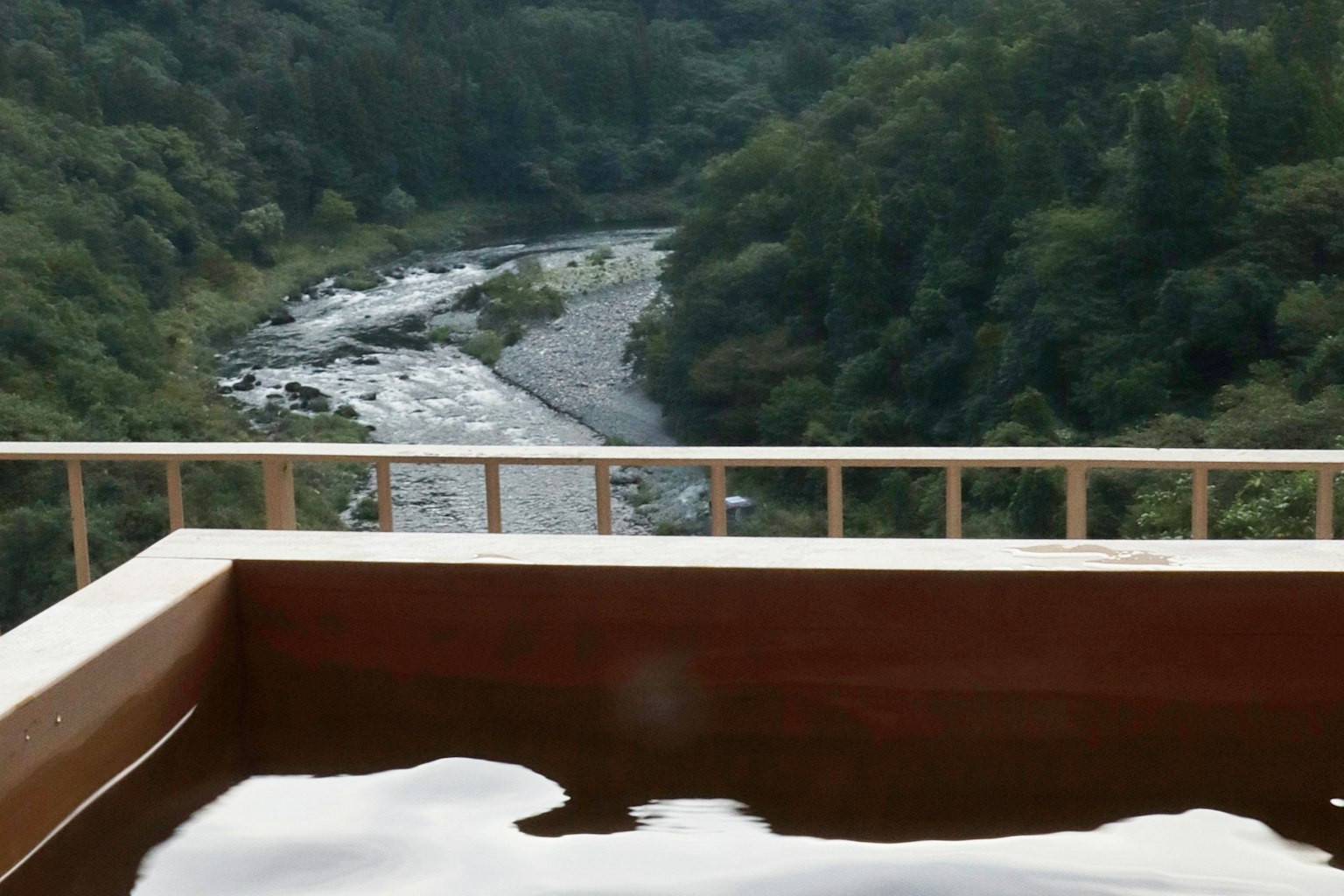 Vista panoramica da una sorgente termale con fiume e montagne verdi