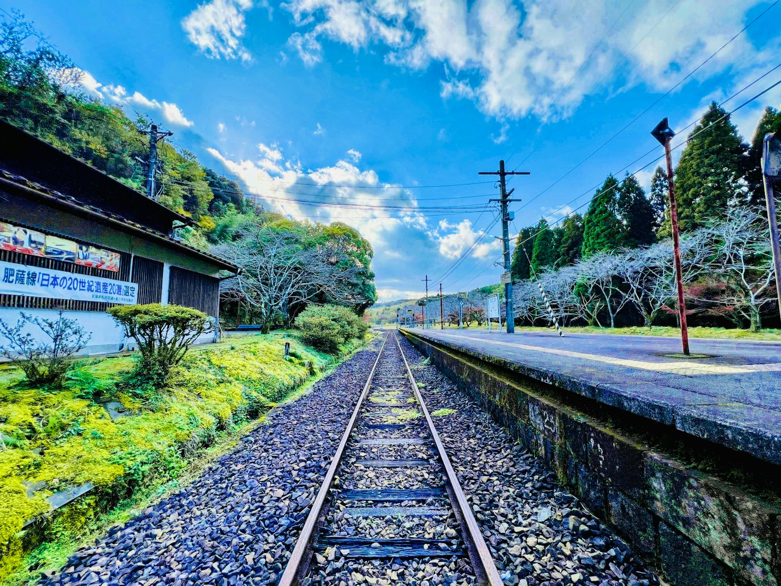 Quiet railway track surrounded by lush greenery and a vibrant blue sky