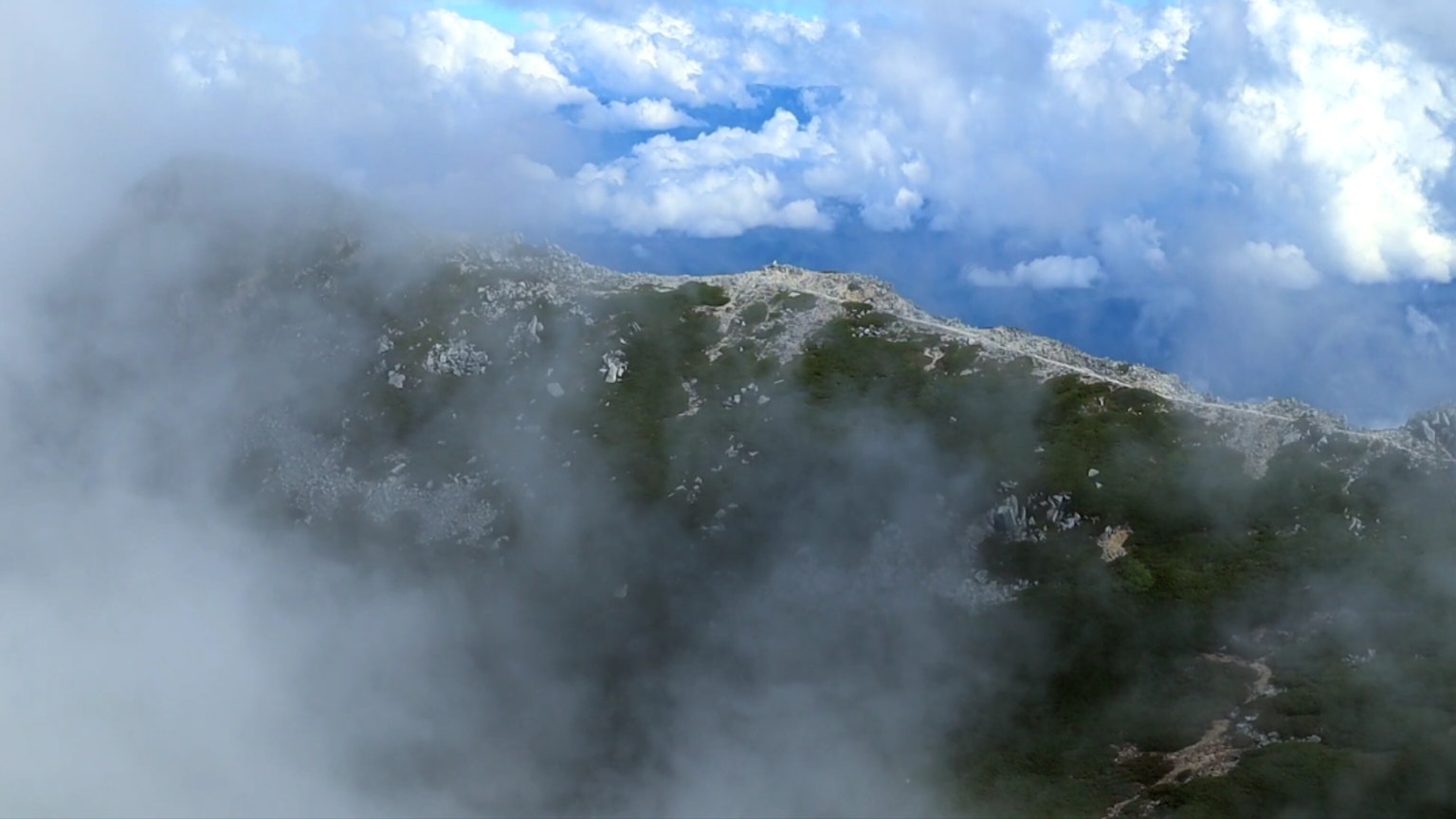 Cima de montaña envuelta en niebla con cielo azul
