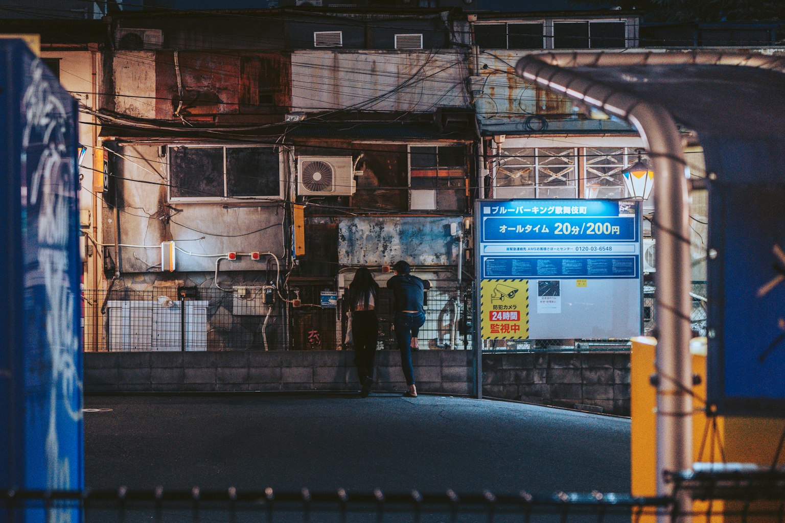 夜晚人們站在老建築前面，背景有藍色標誌