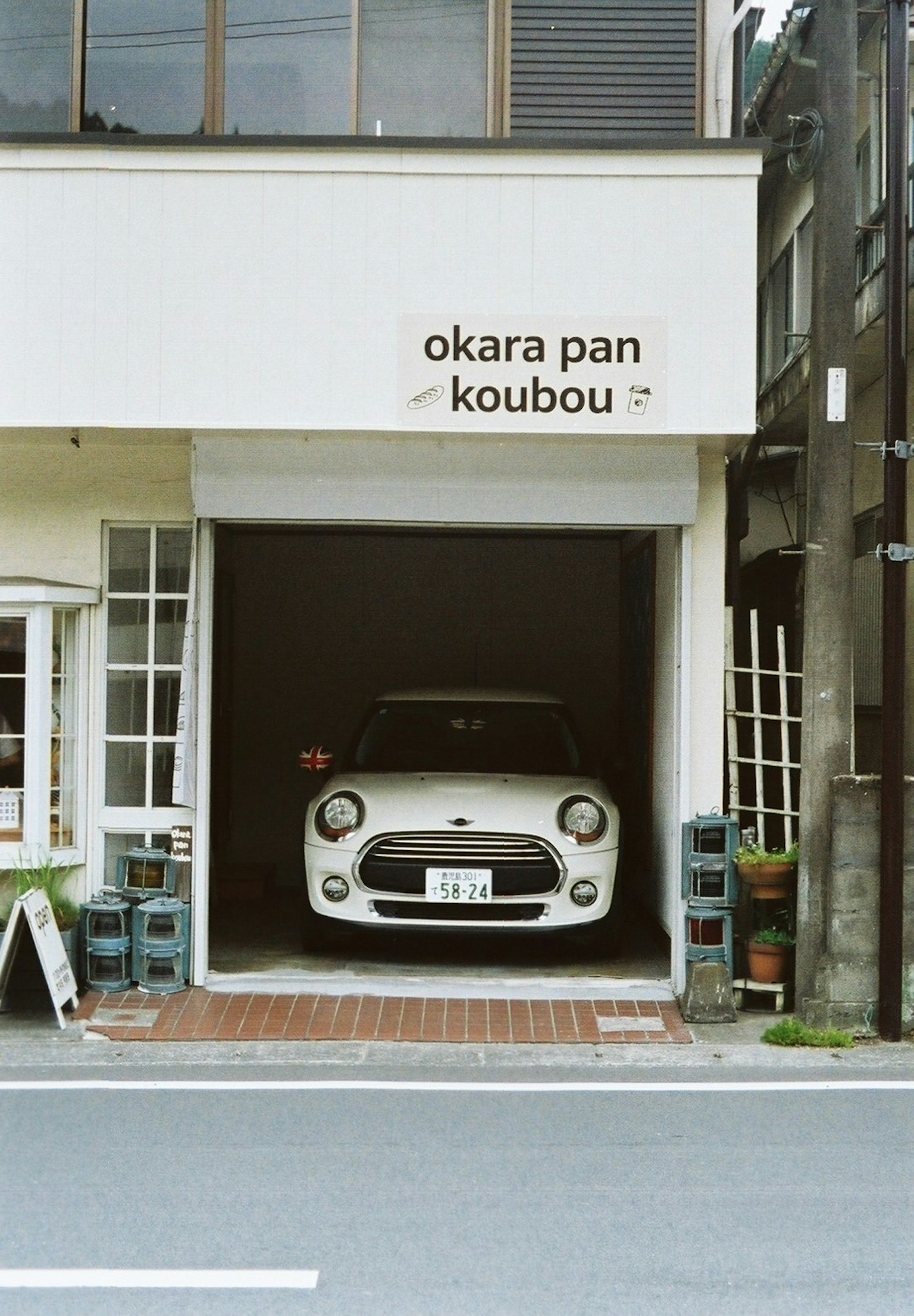 상점의 차고에 주차된 흰색 자동차와 okara pan koubou라는 간판이 있는 이미지