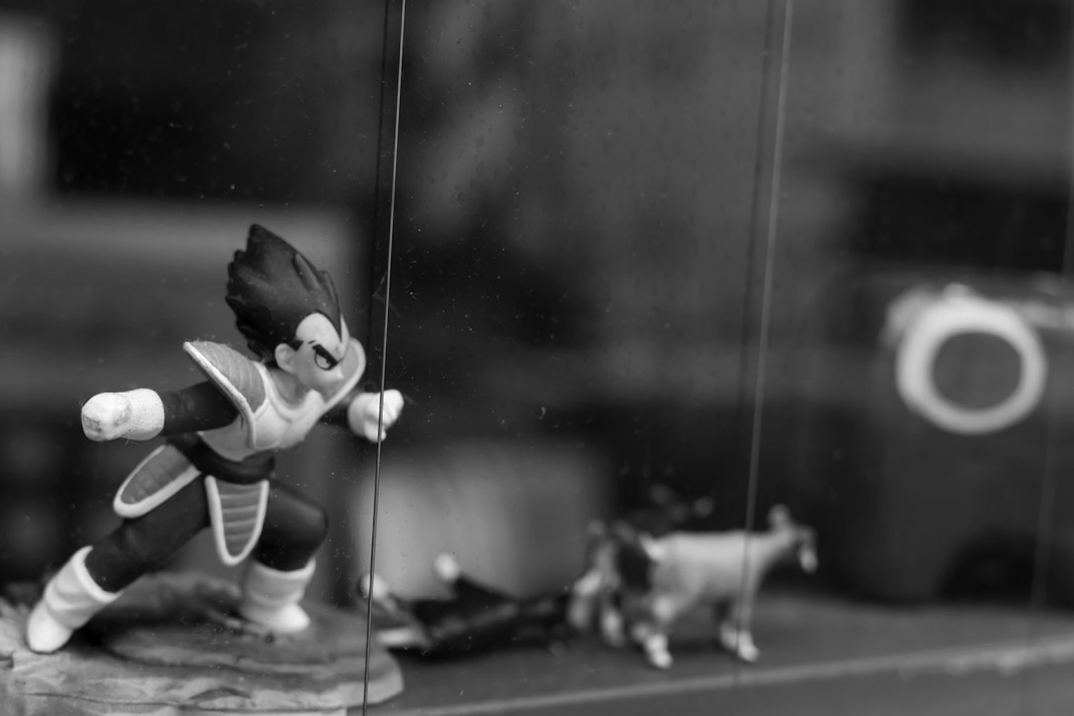 Gambar hitam putih menampilkan figur Vegeta dan figur hewan kecil