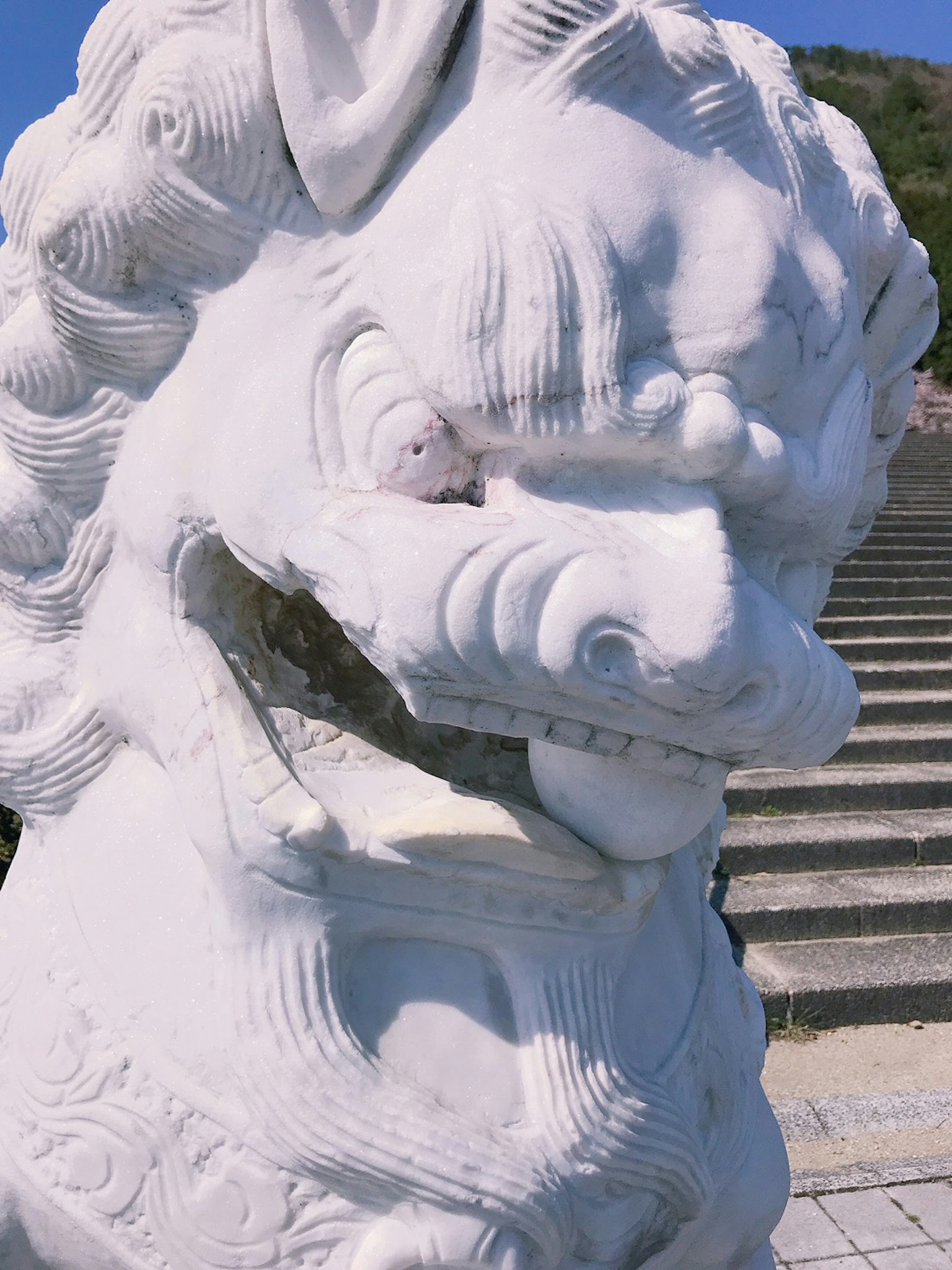 白色獅子雕塑特寫，銳利的眼睛和張開的嘴，背景有樓梯