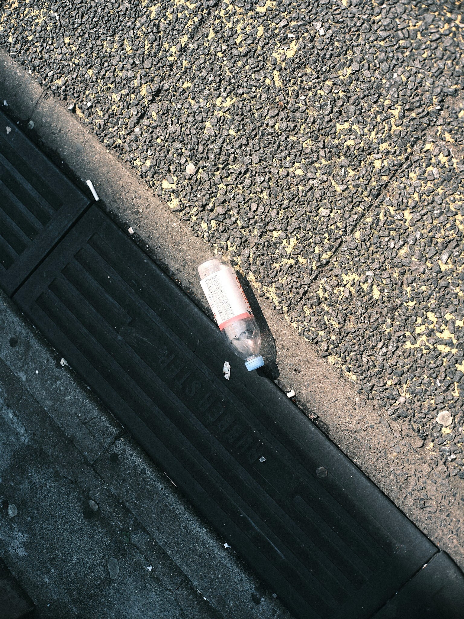 路上の排水溝のそばに置かれた飲み残しのペットボトル