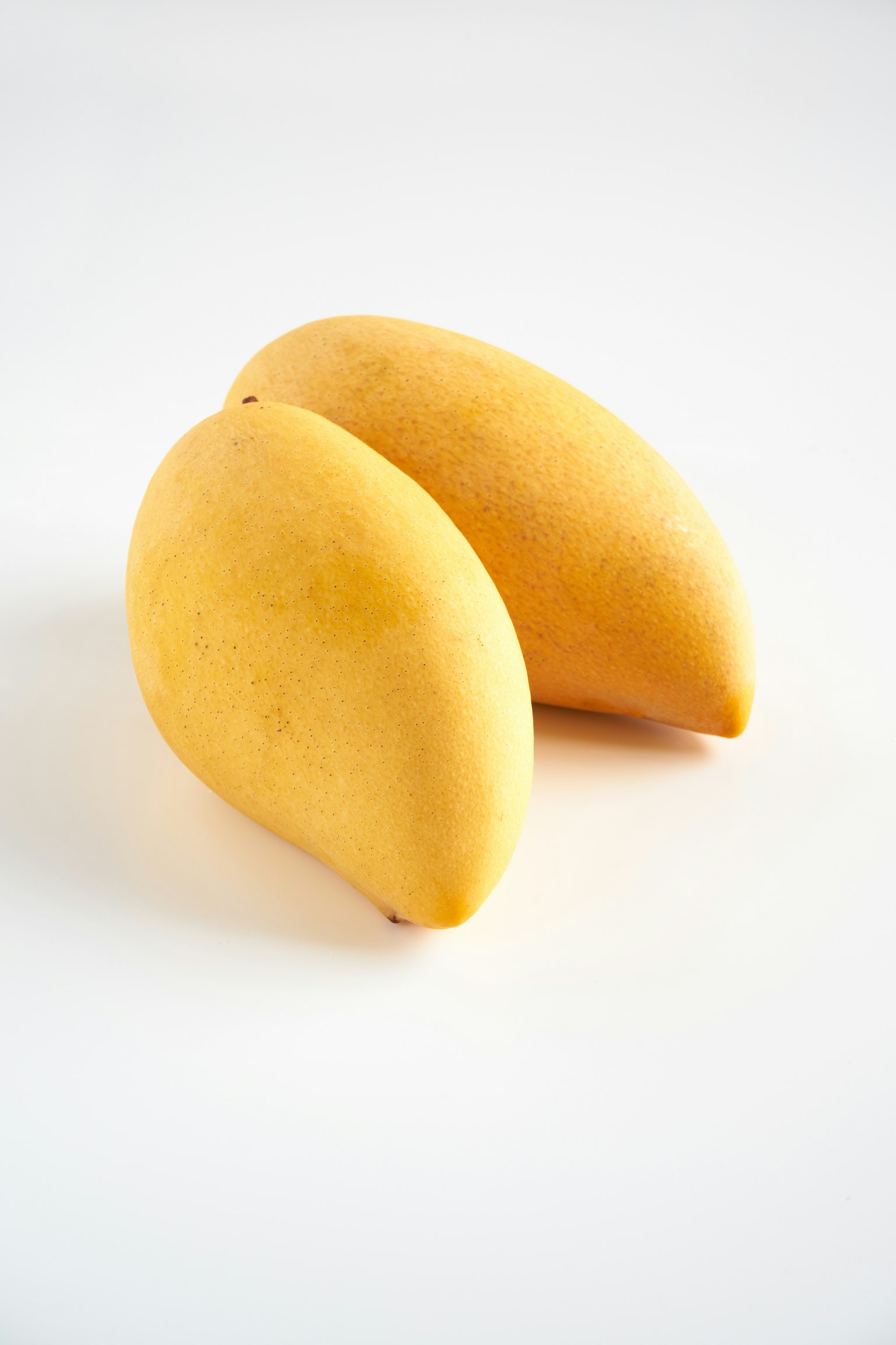 Two ripe mangoes placed on a white background