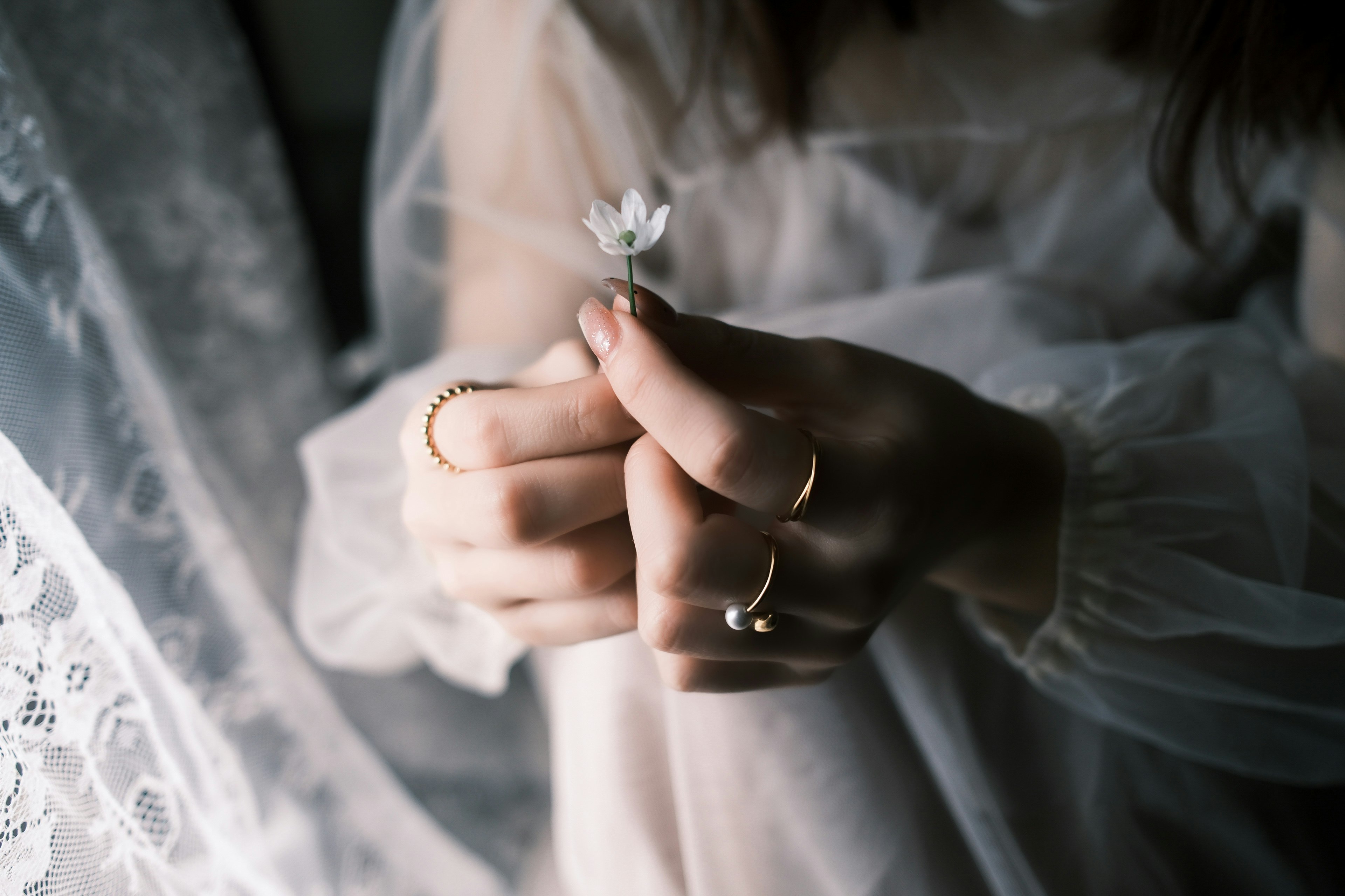 指輪をはめる手とレースのドレスの花飾り