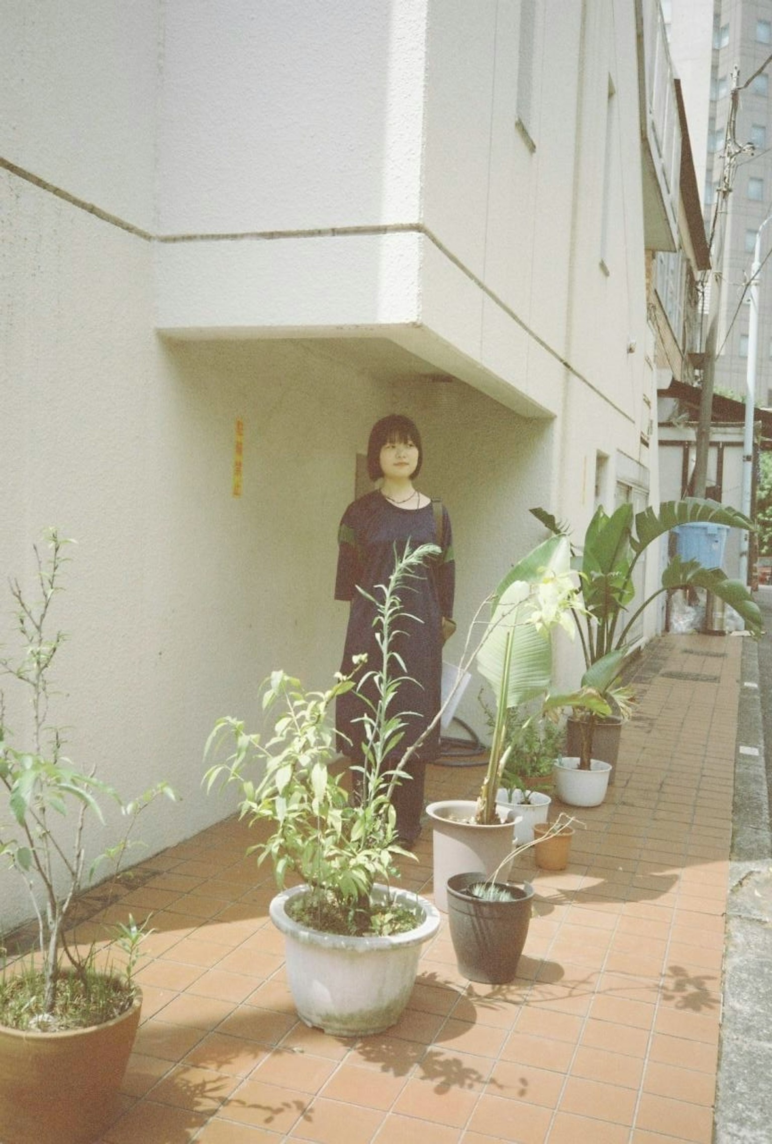 여성이 좁은 골목에서 화분 옆에 서 있다