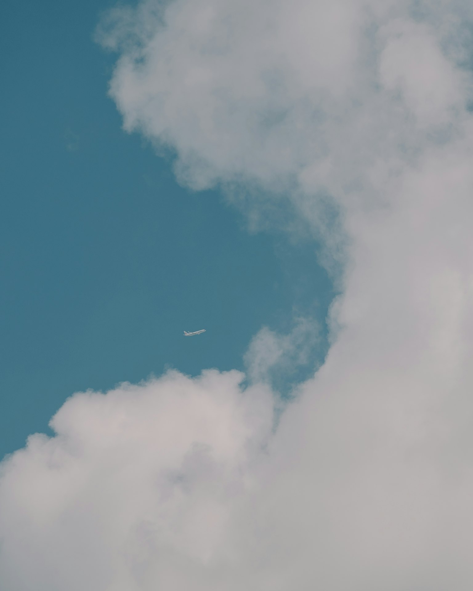 Nuvole bianche in un cielo blu con un piccolo aereo