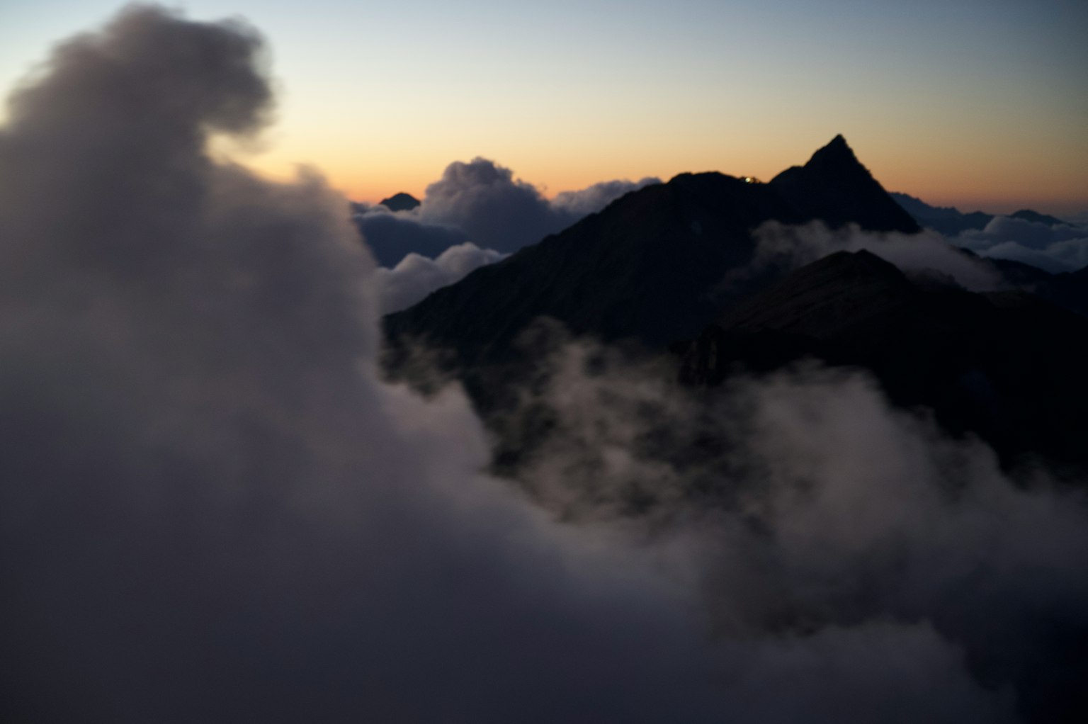 Silhouette d'une montagne entourée de nuages au crépuscule