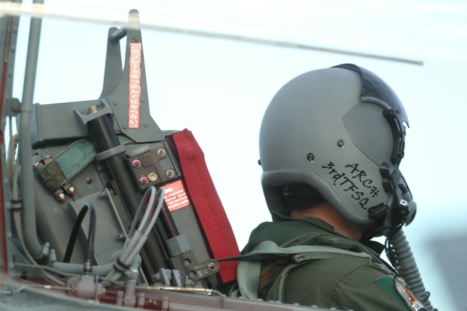 Pilota nel cockpit con casco e attrezzatura visibili