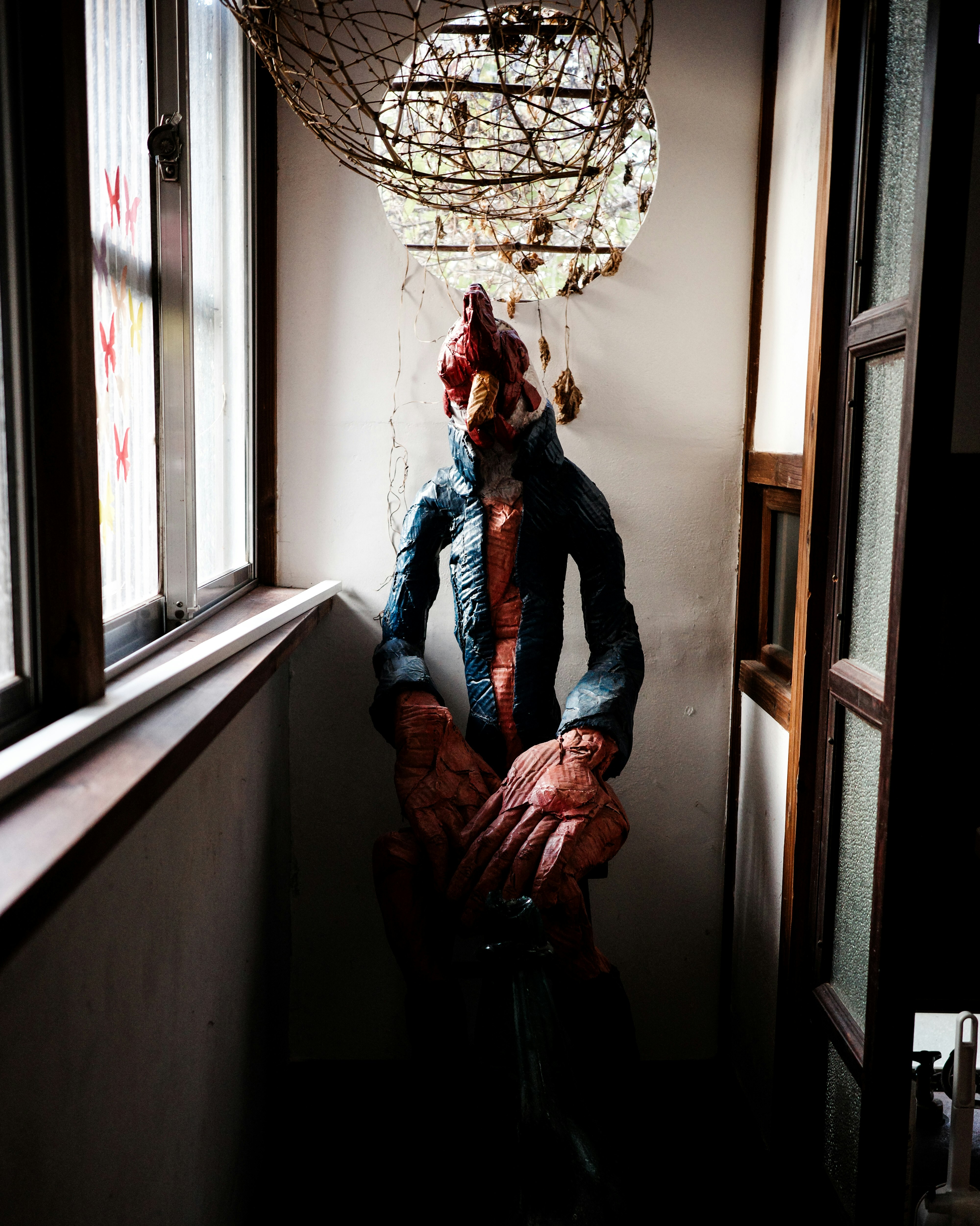 doll-like figures and a person in a narrow indoor hallway with eerie atmosphere